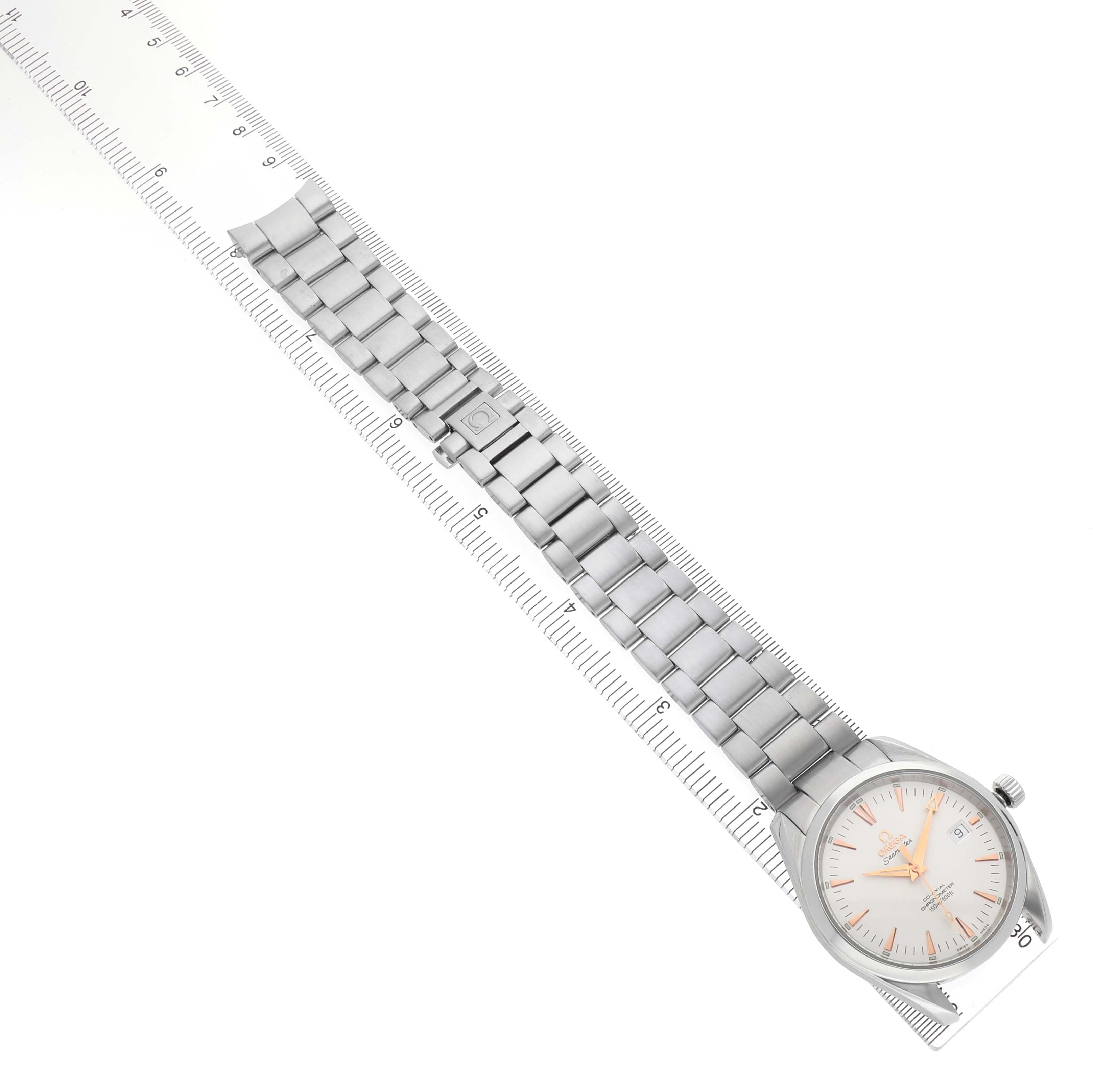 The image shows a top-down view of an Omega Seamaster 2503.34.00 Men's Stainless Steel White Dial watch, focusing on the face and full metal bracelet alongside a ruler.