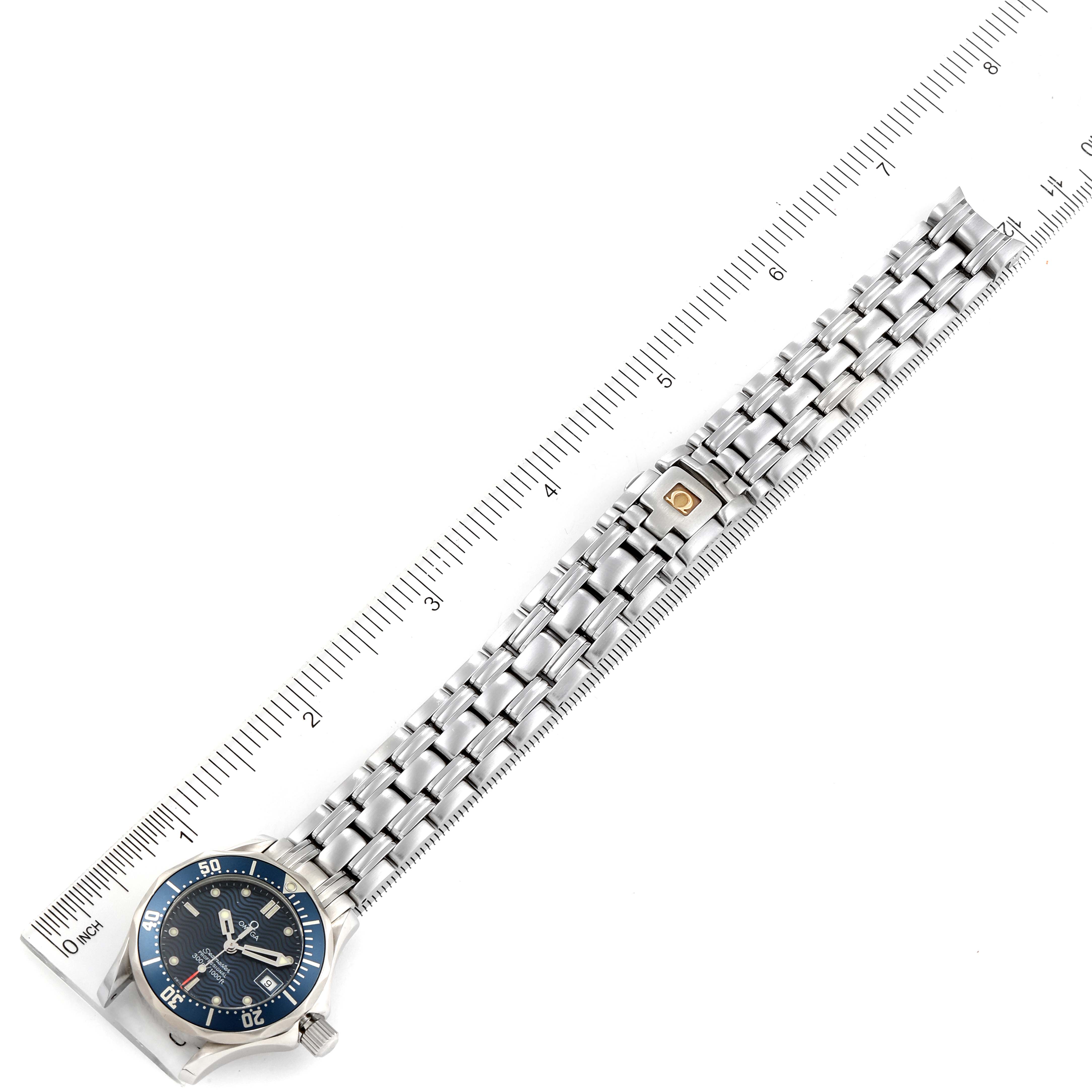 The image shows the Omega 2583.80.00 Women's Stainless Steel Blue Dial 2583.80.00 Women's Stainless Steel Blue Dial Seamaster Diver 300M 28mm Steel Ladies Watch 2583.80.00 laid flat with a ruler, highlighting its size and bracelet.