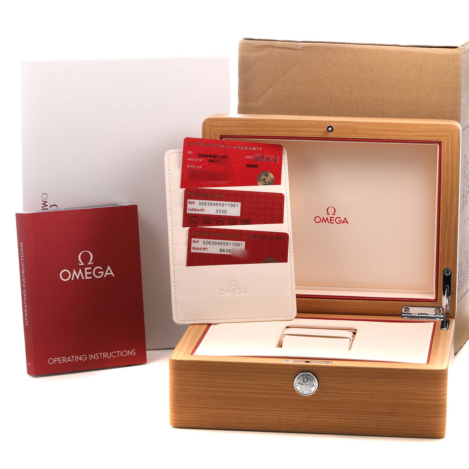 The image shows a Omega Speedmaster 326.30.40.50.11.001 Men's Stainless Steel Red Dial's wooden box, warranty cards, and operating instructions from a frontal angle.