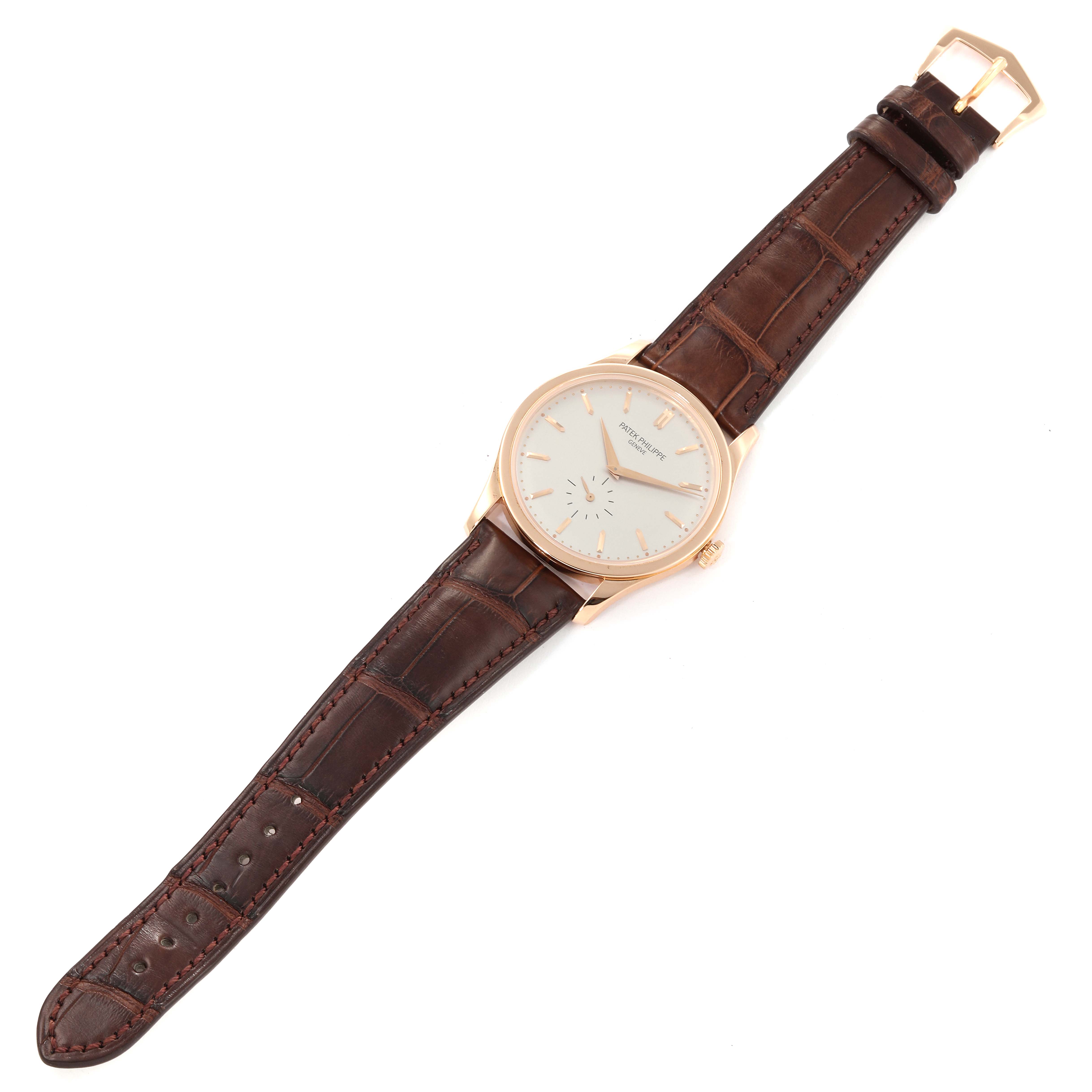 The image shows a top-down view of a Patek Philippe Calatrava 5196R Men
s Rose Gold Silver Dial 5196R Men
s Rose Gold Silver Dial watch featuring a brown leather strap and a gold case.