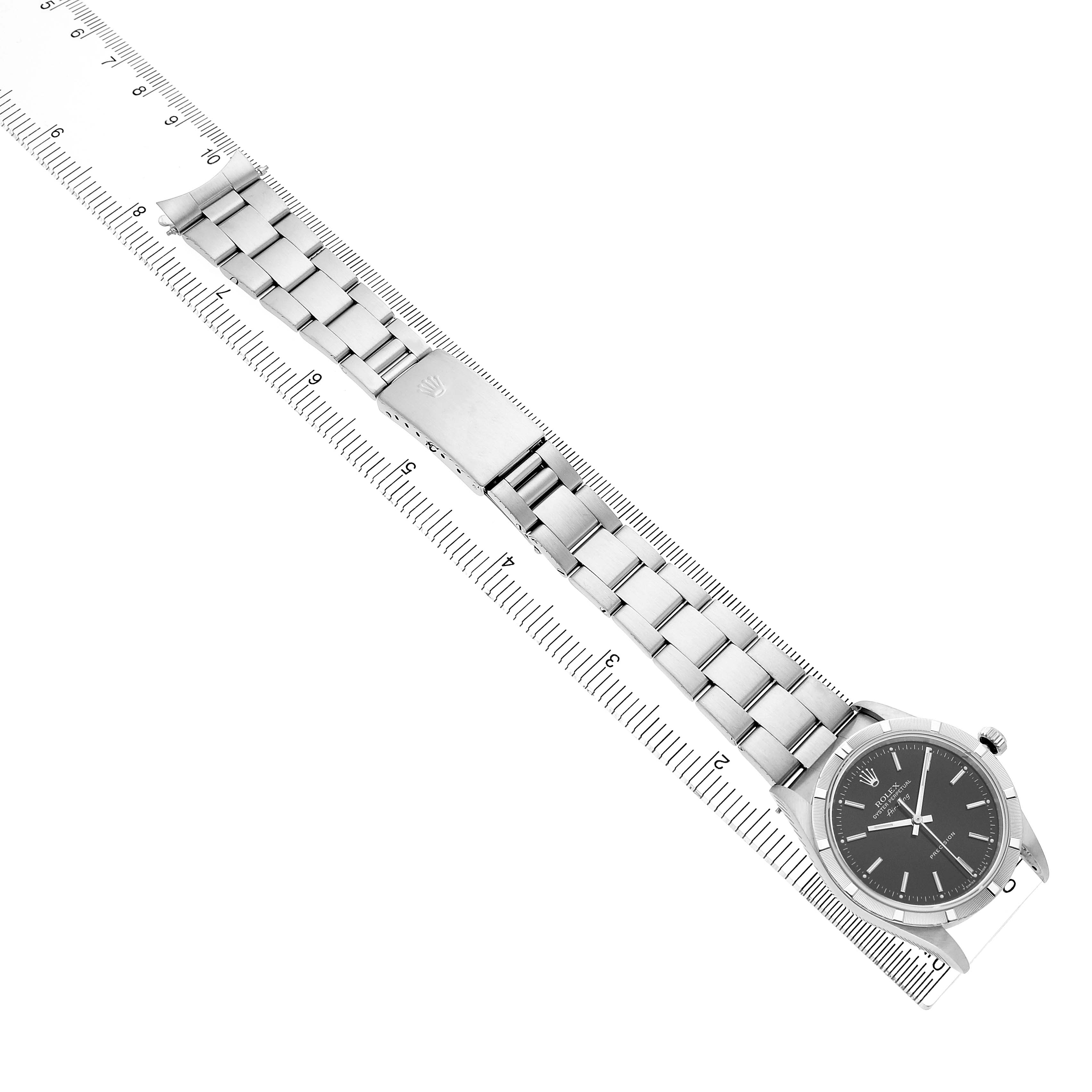 The Rolex Air-King 14010 Men's Stainless Steel Black Dial watch is shown at a top-down angle, displaying its face, bracelet, and clasp alongside a measuring scale.