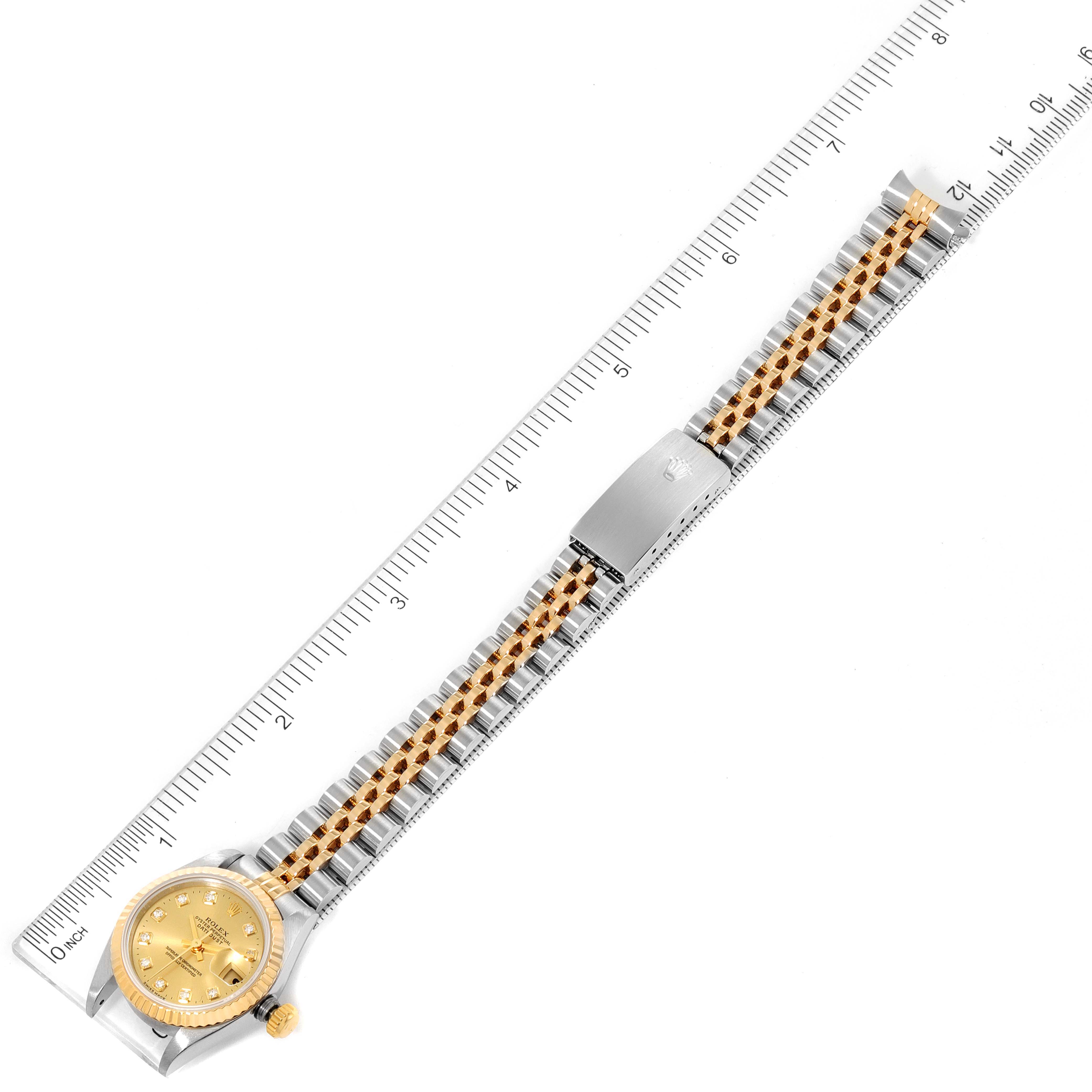 The image shows a Rolex Datejust 69173 Women
s Steel and Gold (two tone) Champagne Dial 69173 Women
s Steel and Gold (two tone) Champagne Dial watch laid flat next to a ruler, displaying the dial face and the entire two-tone bracelet.
