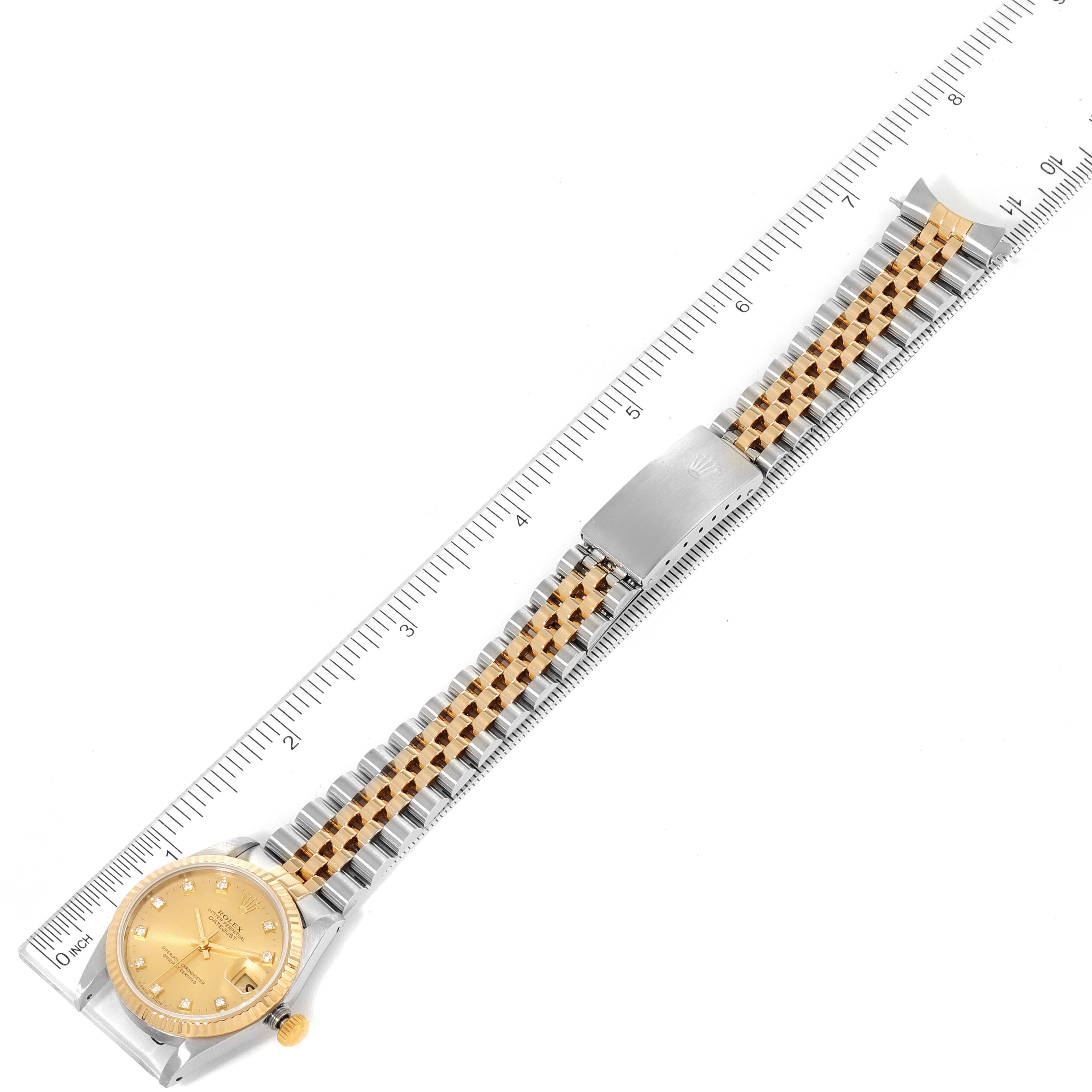 The image shows a top-down view of a Rolex Mid-Size 68273 Women's Steel and Gold (two tone) Champagne Dial 68273 Women's Steel and Gold (two tone) Champagne Dial model watch including the face, case, bracelet, and clasp against a ruler.