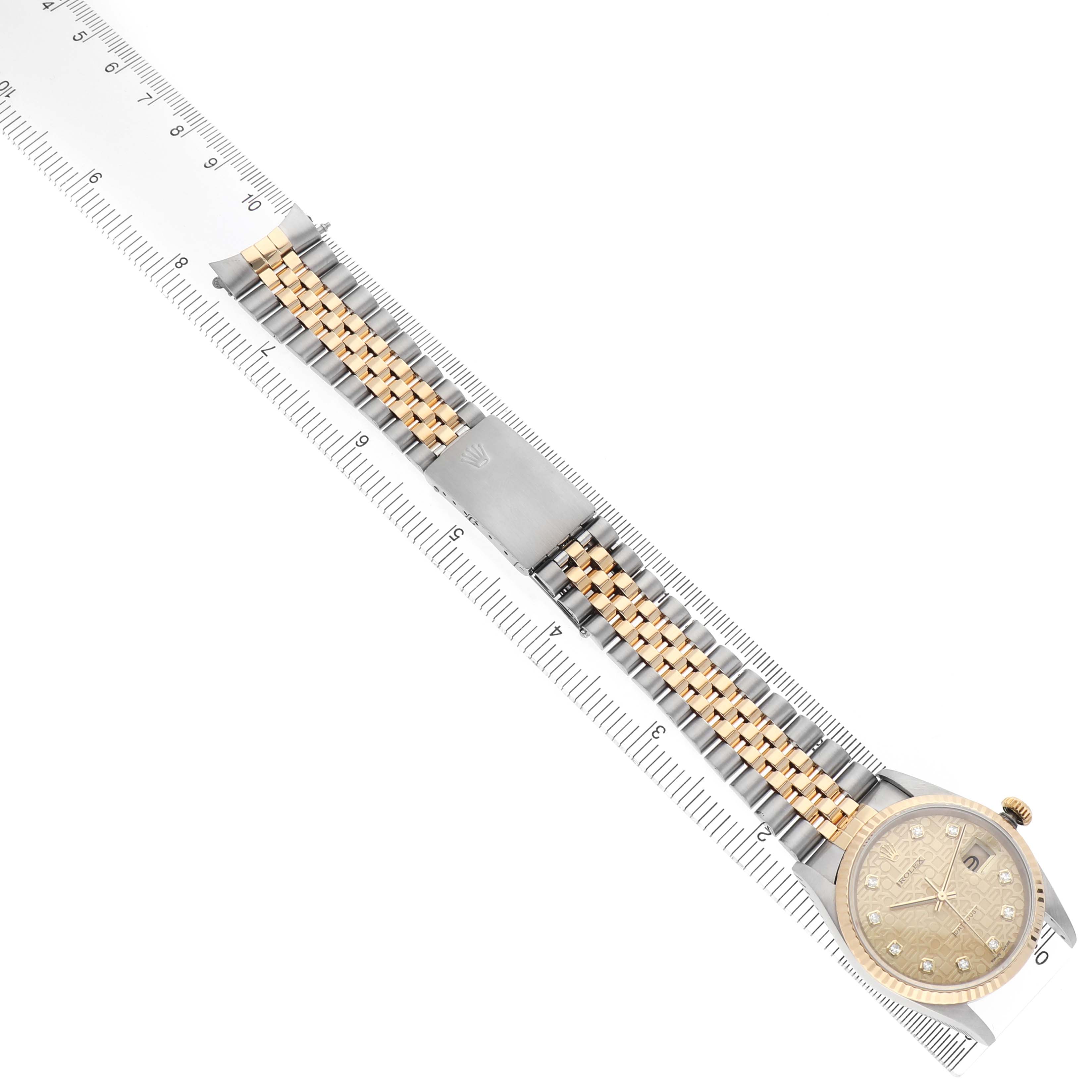 The Rolex Datejust 16233 Men's Stainless Steel Champagne Dial watch is shown from an overhead angle, displaying the dial, bezel, and two-tone bracelet alongside a ruler.