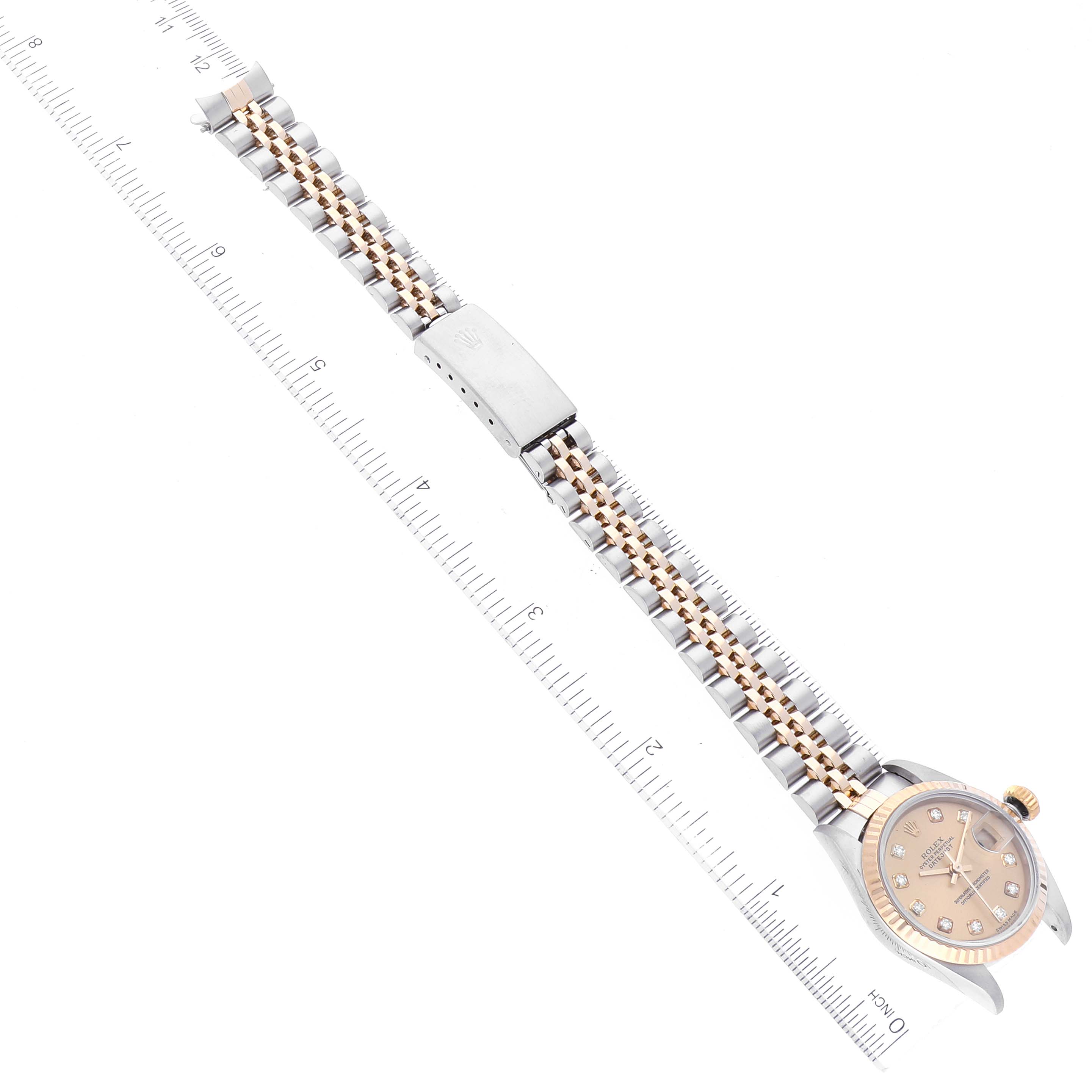 The Rolex Datejust 79173 Women's Steel and Gold (two tone) Champagne Dial 79173 Women's Steel and Gold (two tone) Champagne Dial watch is shown from a top-down angle, displaying the face and the entire bracelet against a ruler.