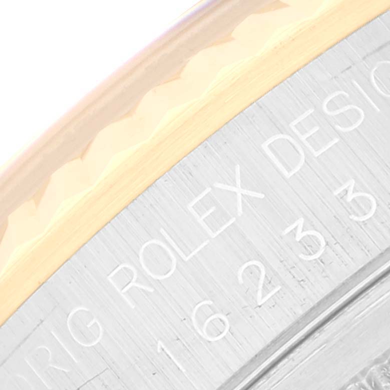 This close-up image shows the engraved bezel part of a Rolex Datejust 16233 Men's Steel and Gold (two tone) Champagne Dial 16233 Men's Steel and Gold (two tone) Champagne Dial watch, including part of its serial number.