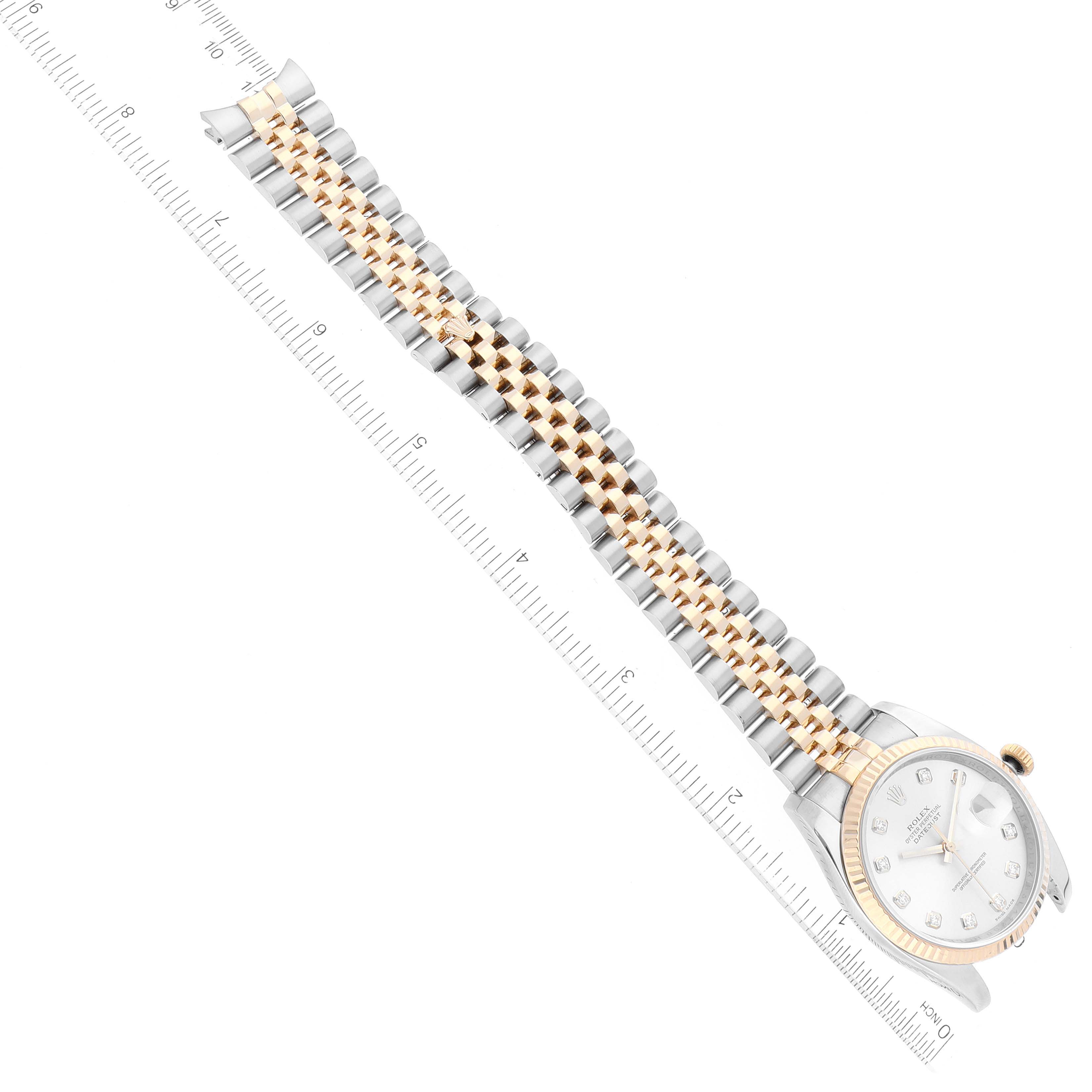 This image shows the Rolex Datejust 116233 Men's Steel and Gold (two tone) Silver Dial 116233 Men's Steel and Gold (two tone) Silver Dial watch at a top view angle, displaying its face, bezel, and two-tone bracelet alongside a ruler.