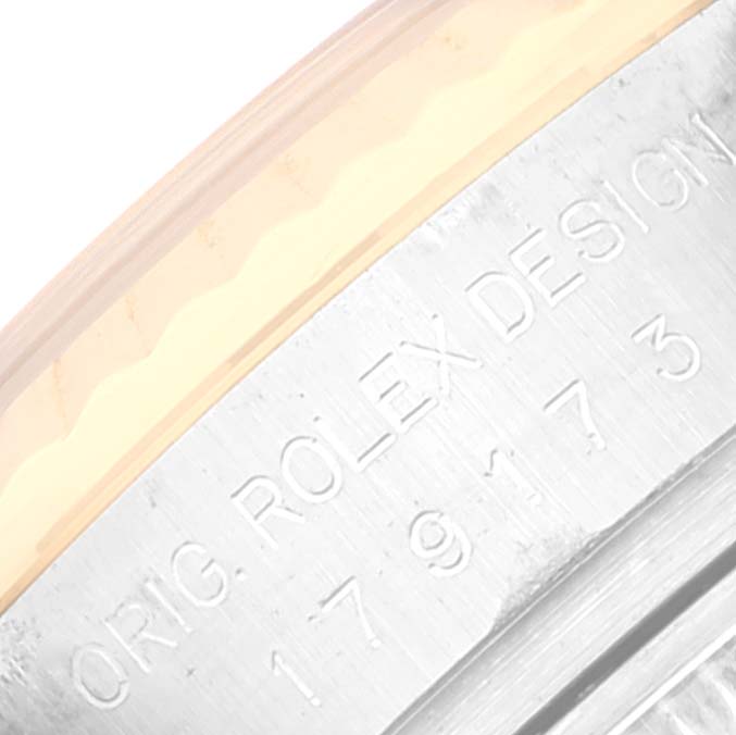 This image shows a close-up of the casing edge of a Rolex Datejust 179173 Women's Steel and Gold (two tone) White Dial 179173 Women's Steel and Gold (two tone) White Dial watch inscribed with "ORIG. ROLEX DESIGN."