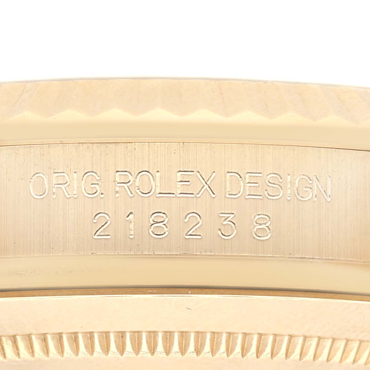 This close-up image shows the engraved bezel of a Rolex President 218238 Men's Yellow Gold White Dial 218238 Men's Yellow Gold White Dial model watch, highlighting its design number.