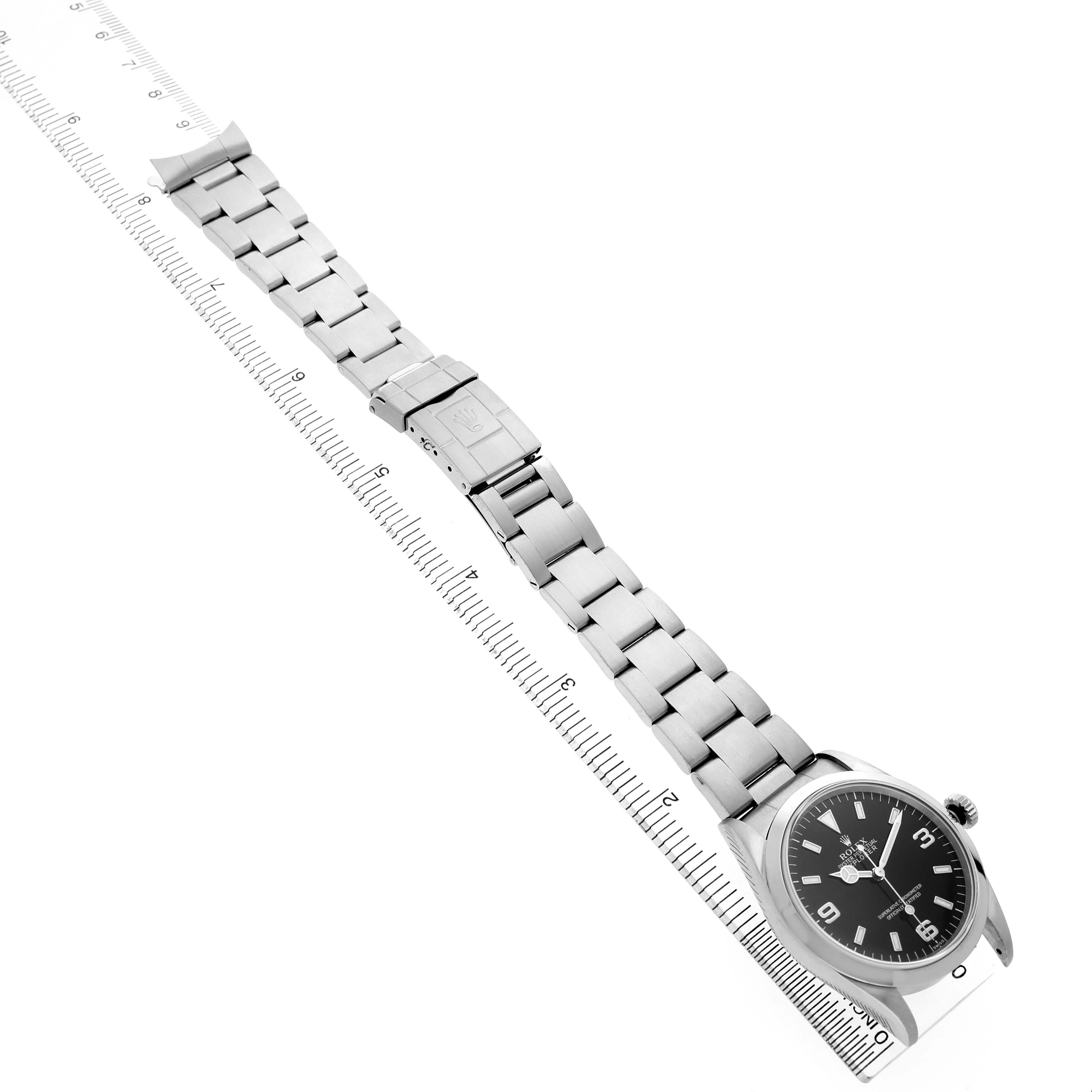The Rolex Explorer 14270 Men's Stainless Steel Black Dial watch is shown from a top-down angle, featuring the entire bracelet and face next to a ruler for scale.