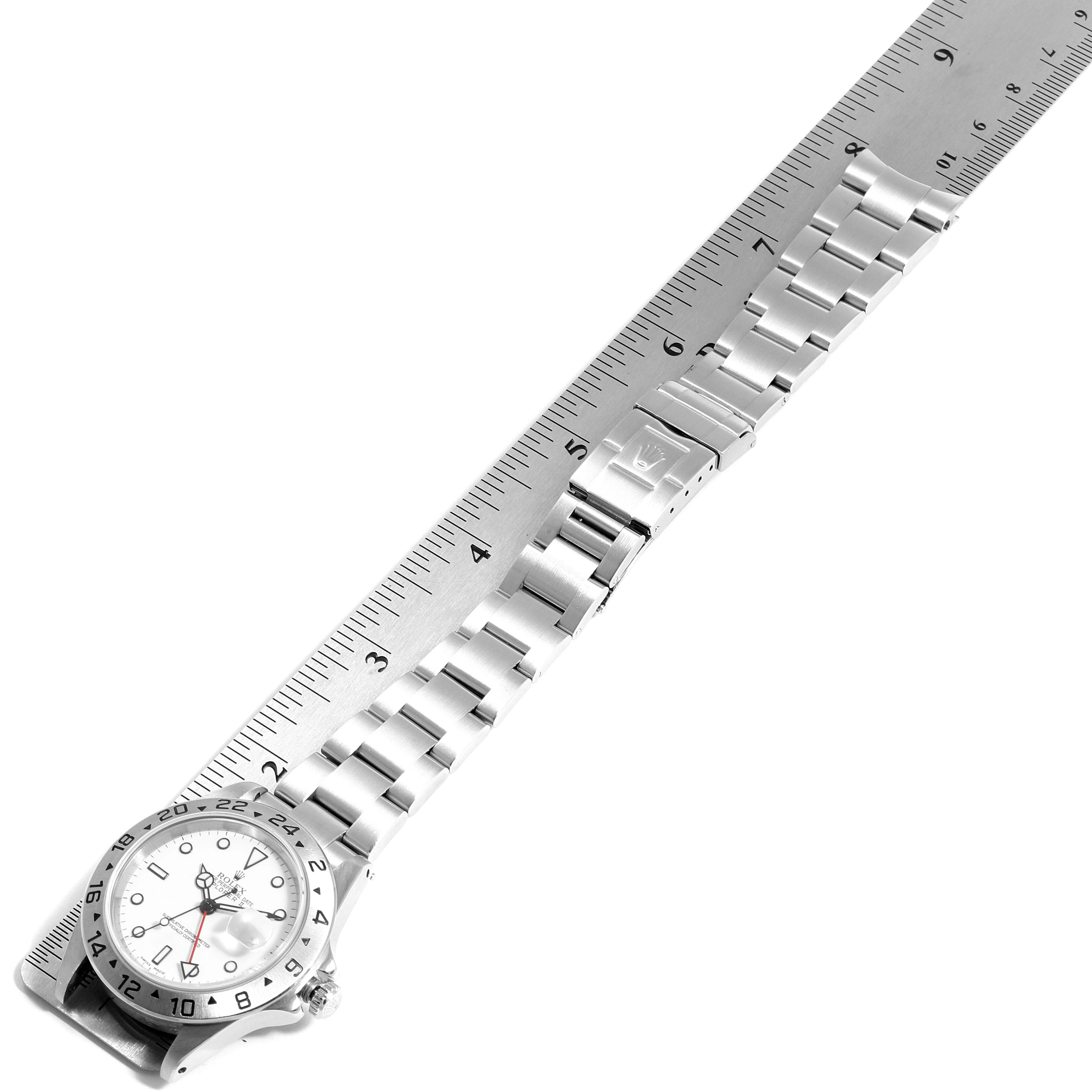The image shows a Rolex Explorer 16570 Men
s Stainless Steel White Dial 16570 Men
s Stainless Steel White Dial watch laid flat next to a ruler, displaying its bracelet and clasp from a top-down angle.