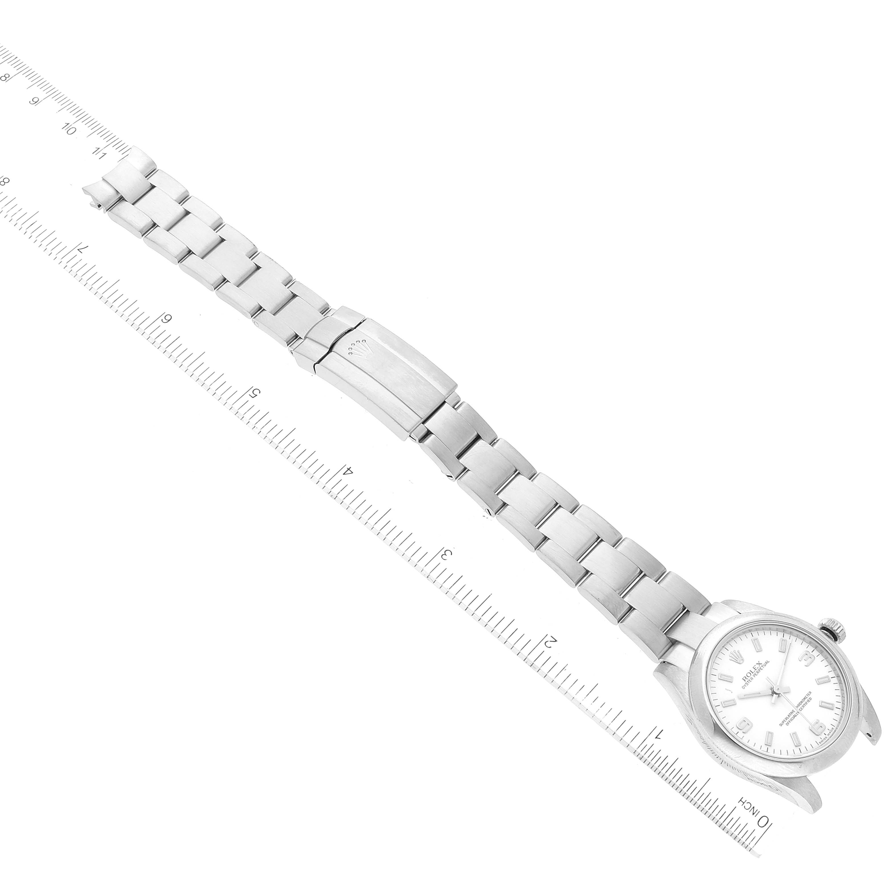 The image shows a Rolex Mid-Size 177200 Women's Stainless Steel White Dial 177200 Women's Stainless Steel White Dial watch with a white dial and silver bracelet, viewed from a top-down angle and accompanied by a measuring ruler.