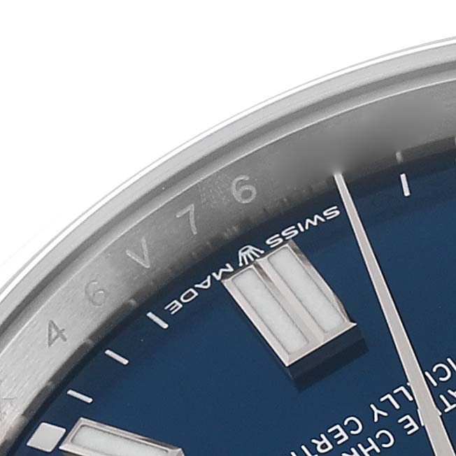 This close-up image of a Rolex Oyster Perpetual 126000 Men's Stainless Steel Blue Dial 126000 Men's Stainless Steel Blue Dial watch showcases a portion of the blue dial, luminescent hour markers, and the edge of the bezel.