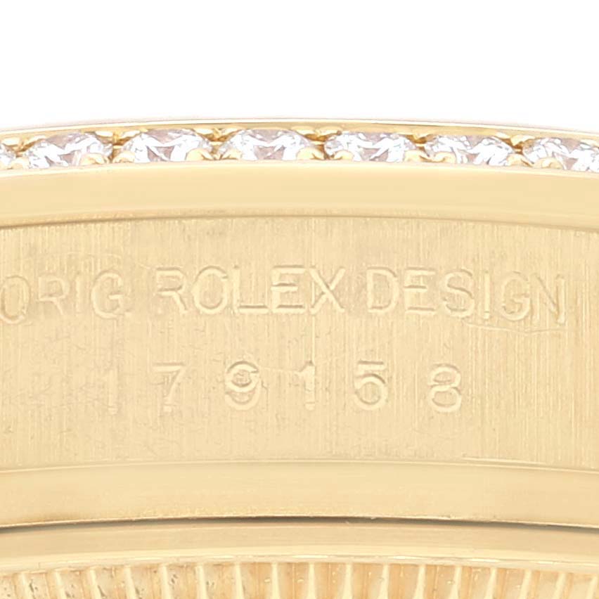 This close-up image shows the engraved side of a Rolex President 179158 Women
s Yellow Gold Champagne Dial 179158 Women
s Yellow Gold Champagne Dial model watch with diamonds on the bezel.