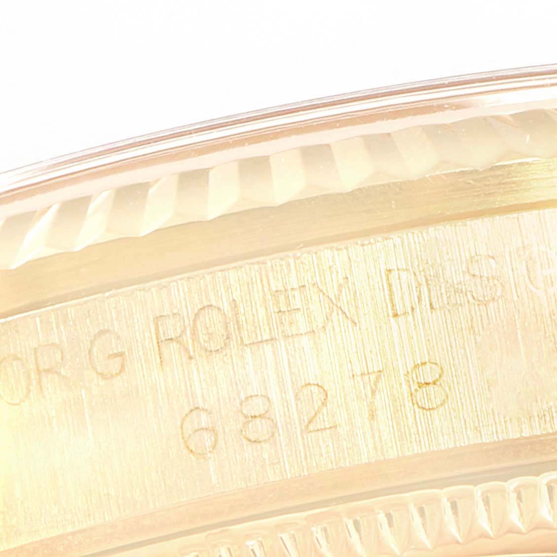 This close-up image shows the bezel and part of the case of a Rolex President 68278 Women
s Yellow Gold Champagne Dial 68278 Women
s Yellow Gold Champagne Dial model, focusing on the engraved serial number.
