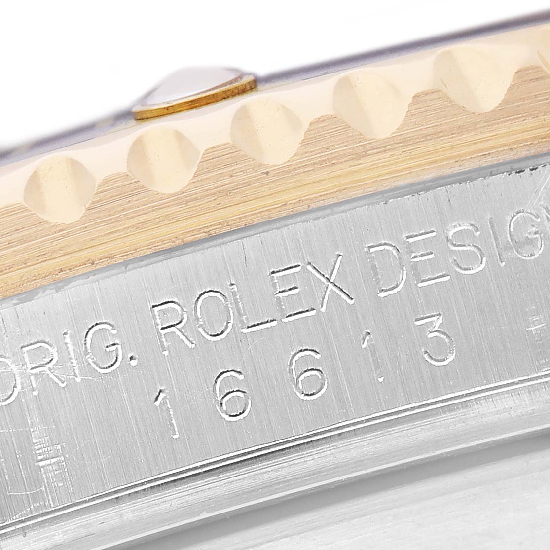 The image shows a close-up of the case side of a Rolex Submariner 16613 Men's Steel and Gold (two tone) Blue Dial, highlighting the engraved model number and "ROLEX DESIGN" text.