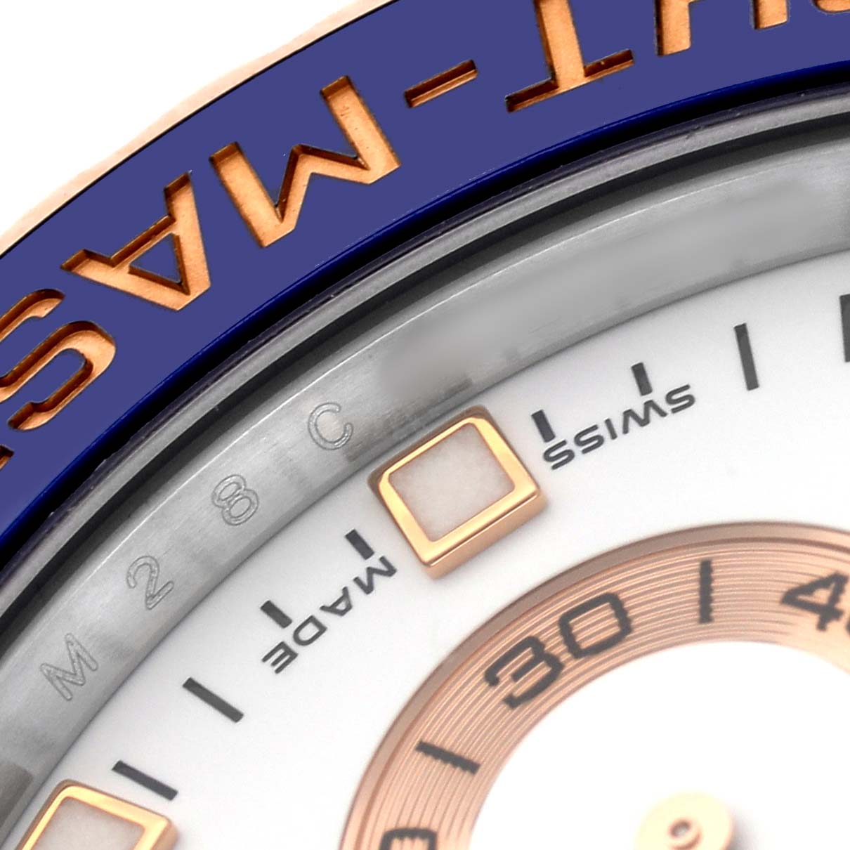 The image shows a close-up of the Rolex Yacht-Master 116681 Men's Steel and Gold (two tone) White Dial's bezel, dial markers, and part of the chapter ring.