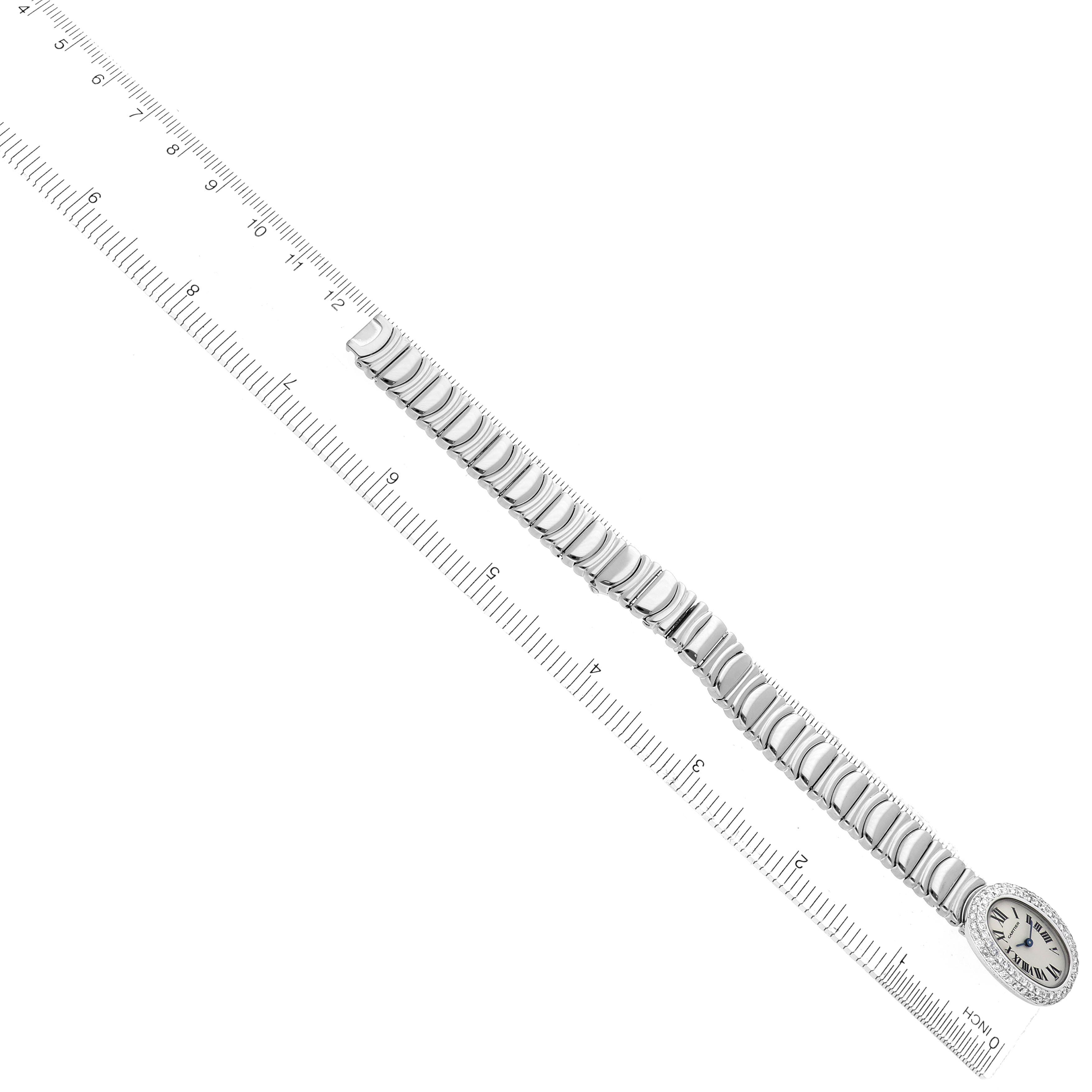 The Cartier Baignoire WB095W2 Women's White Gold Silver Dial WB095W2 Women's White Gold Silver Dial watch is shown from a top view with its oval face and metal bracelet beside a ruler for scale.