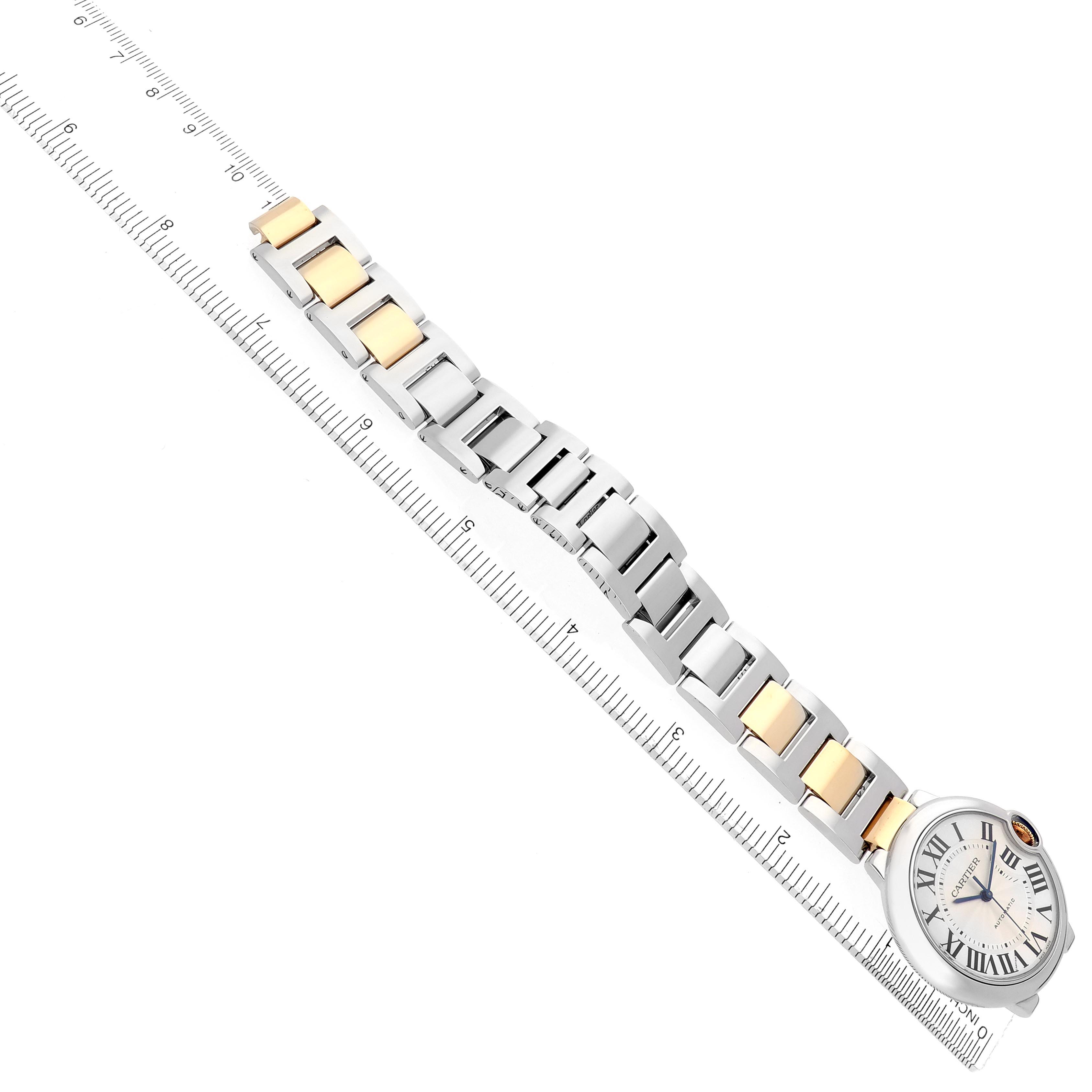 The Cartier Ballon Bleu W2BB0012 Women
s Steel and Gold (two tone) Silver Dial W2BB0012 Women
s Steel and Gold (two tone) Silver Dial watch is shown from a top view, highlighting its two-tone bracelet and round case next to a ruler.