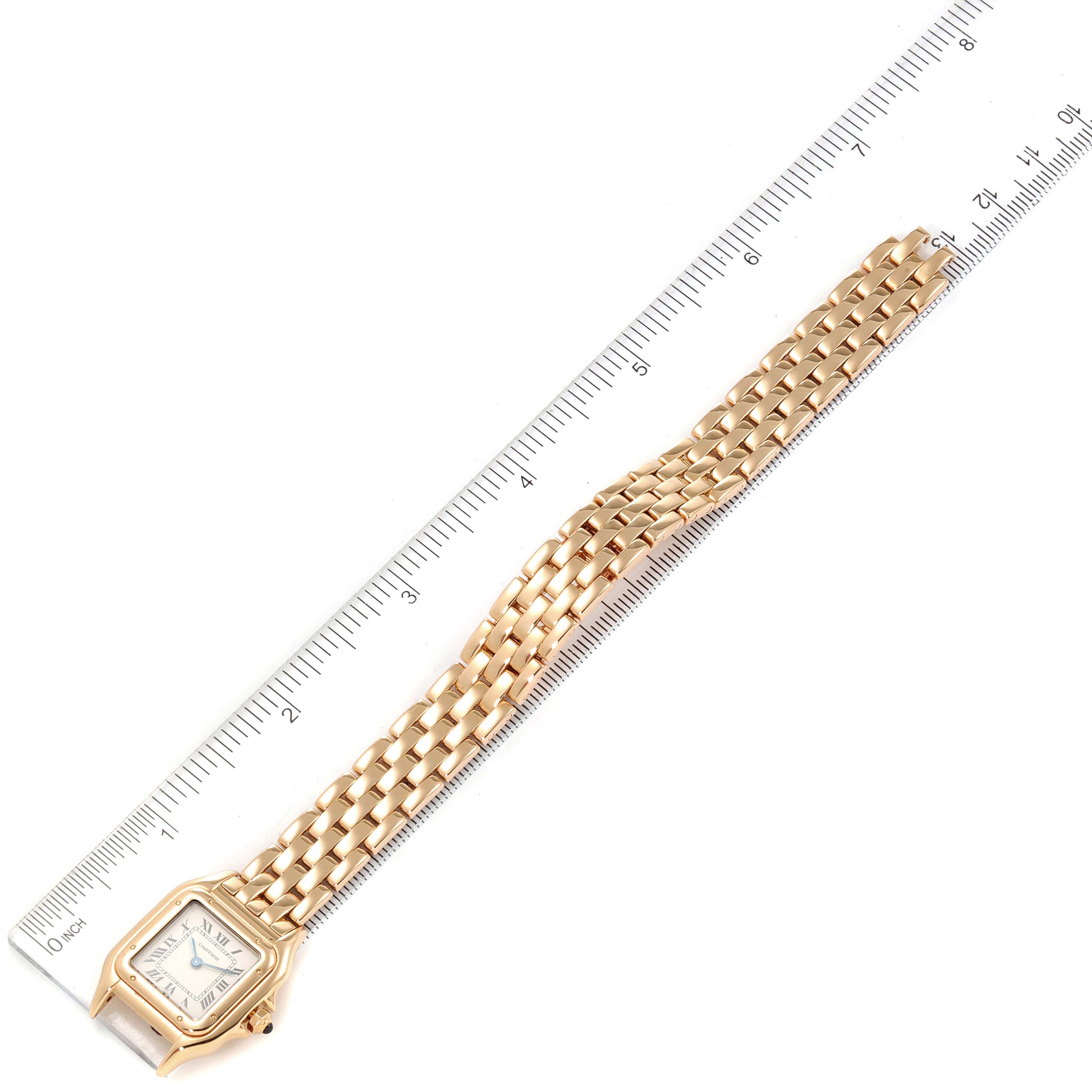 This image shows a Cartier Panthere W25022B9 Women's Yellow Gold Silver Dial W25022B9 Women's Yellow Gold Silver Dial watch laid flat alongside a ruler, displaying its entire band and face from an overhead angle.