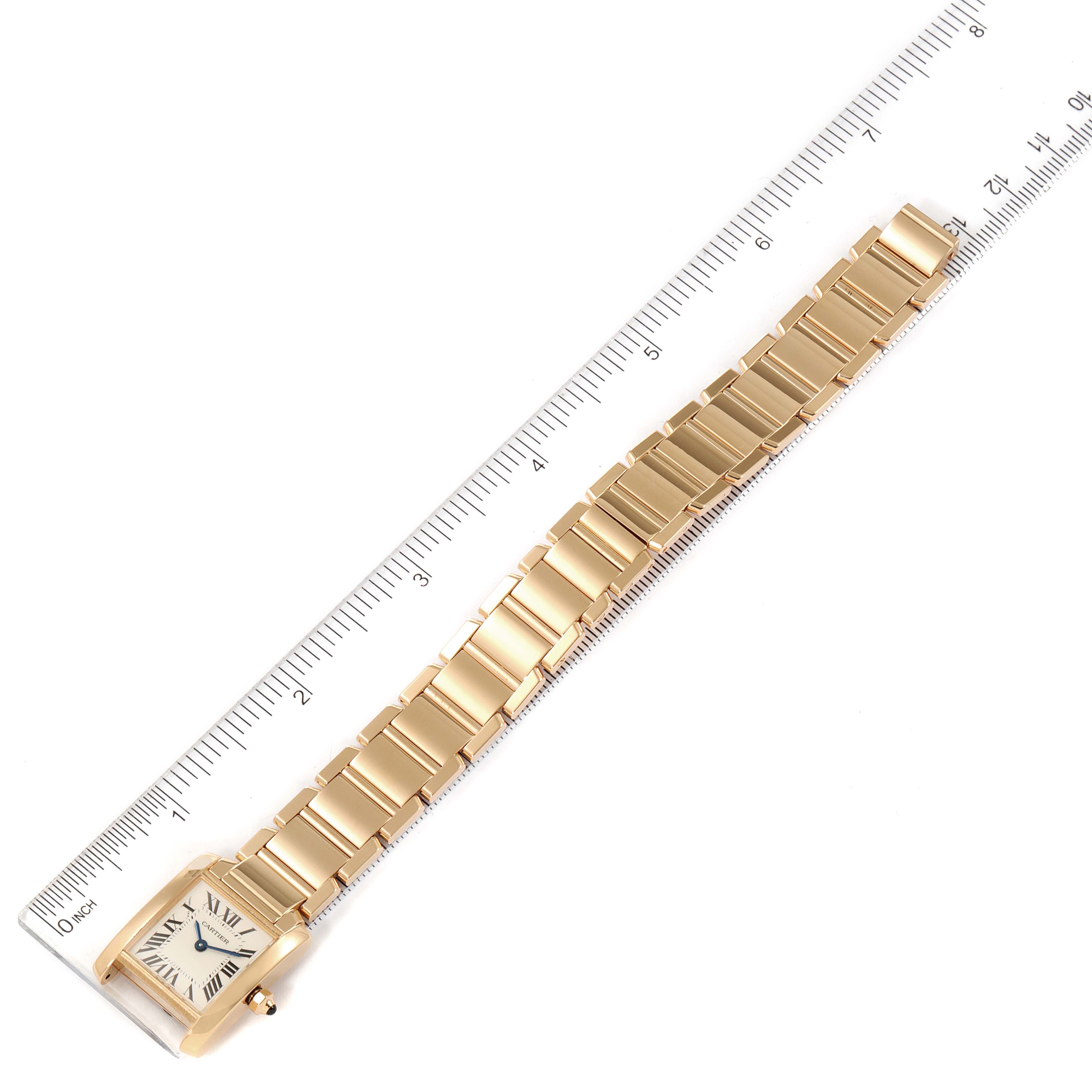 The Cartier Tank Francaise W50002N2 Women's Yellow Gold Silver Dial W50002N2 Women's Yellow Gold Silver Dial watch is shown from a top-down angle, displaying the face, case, and entire bracelet next to a ruler for scale.