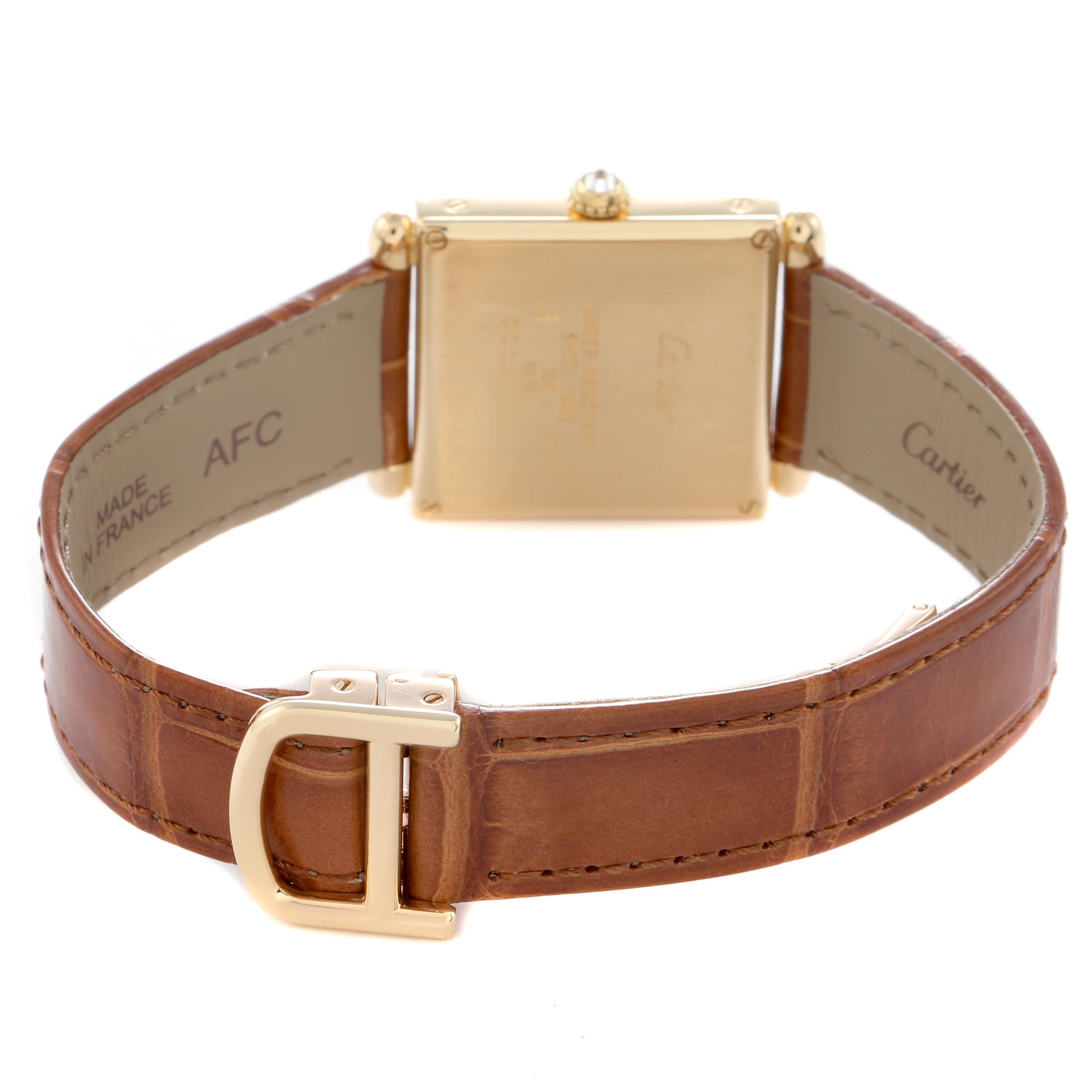 The Tank Obus by Cartier is shown from the back, highlighting its gold case, brown leather strap, and buckle.