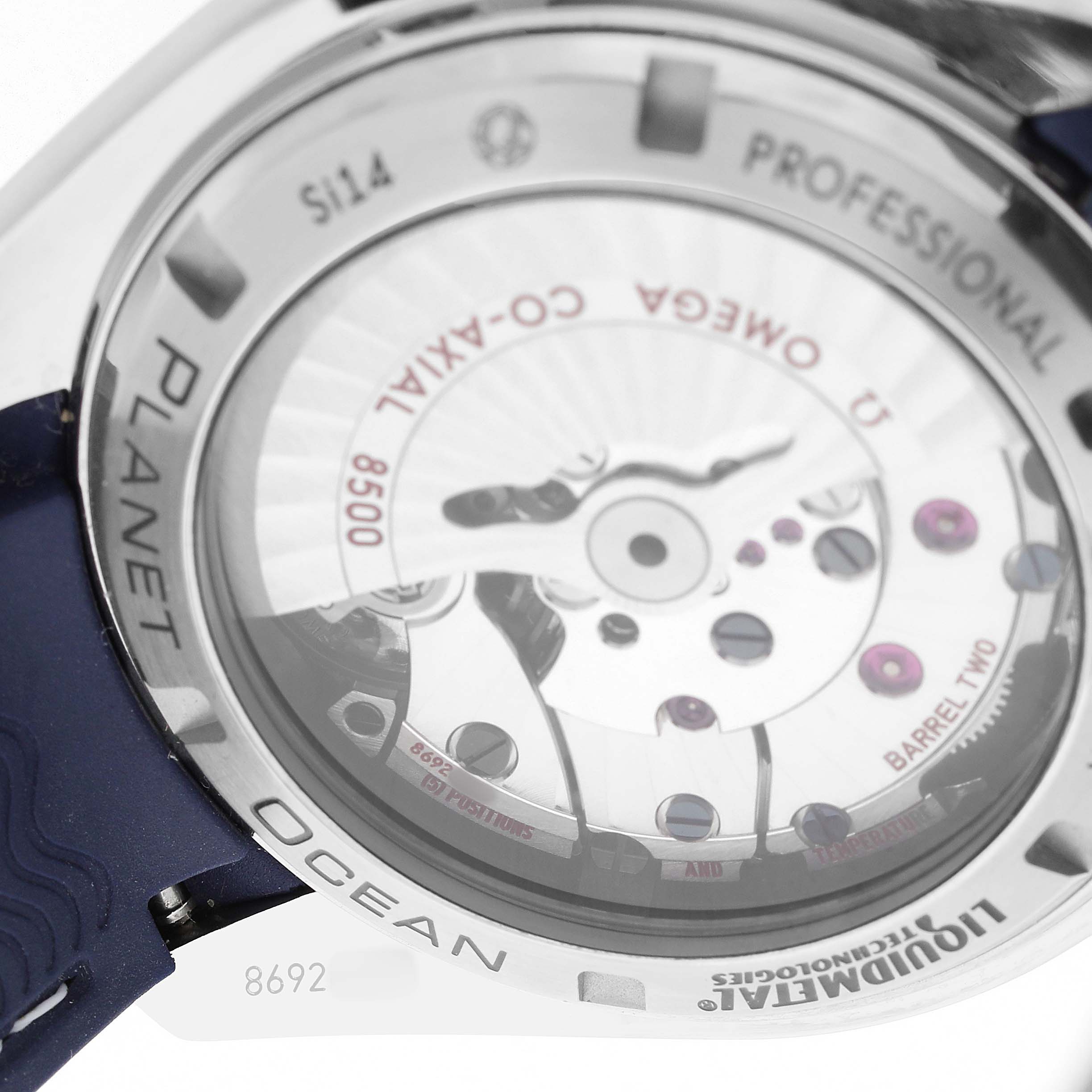 The image shows the back of the Omega Planet Ocean 232.92.42.21.03.001 Men's Titanium Blue Dial watch, featuring the movement and inscriptions.