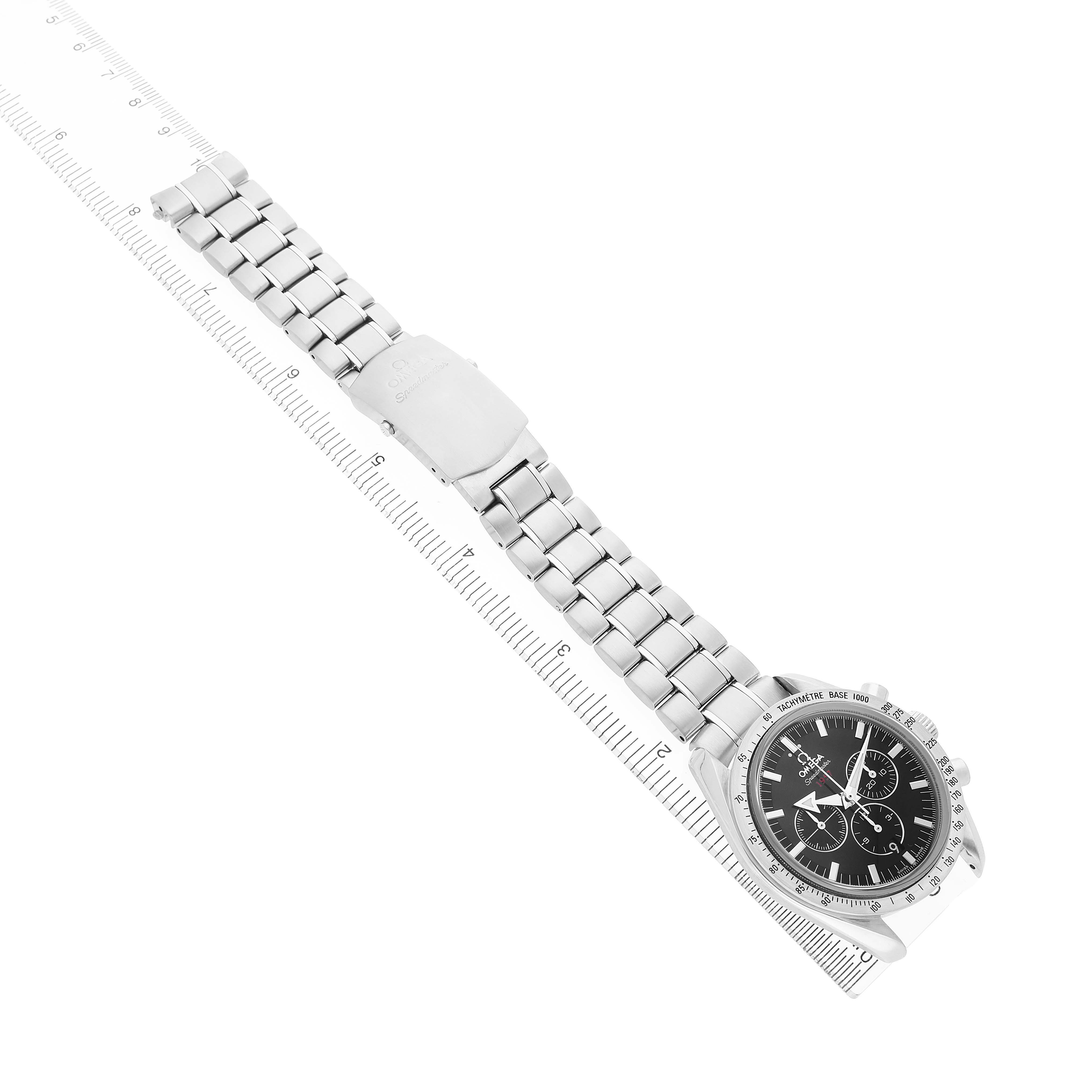 The Omega Speedmaster 321.10.42.50.01.001 Men's Stainless Steel Black Dial watch is shown at an oblique angle, displaying the full bracelet and face, alongside a ruler for scale.