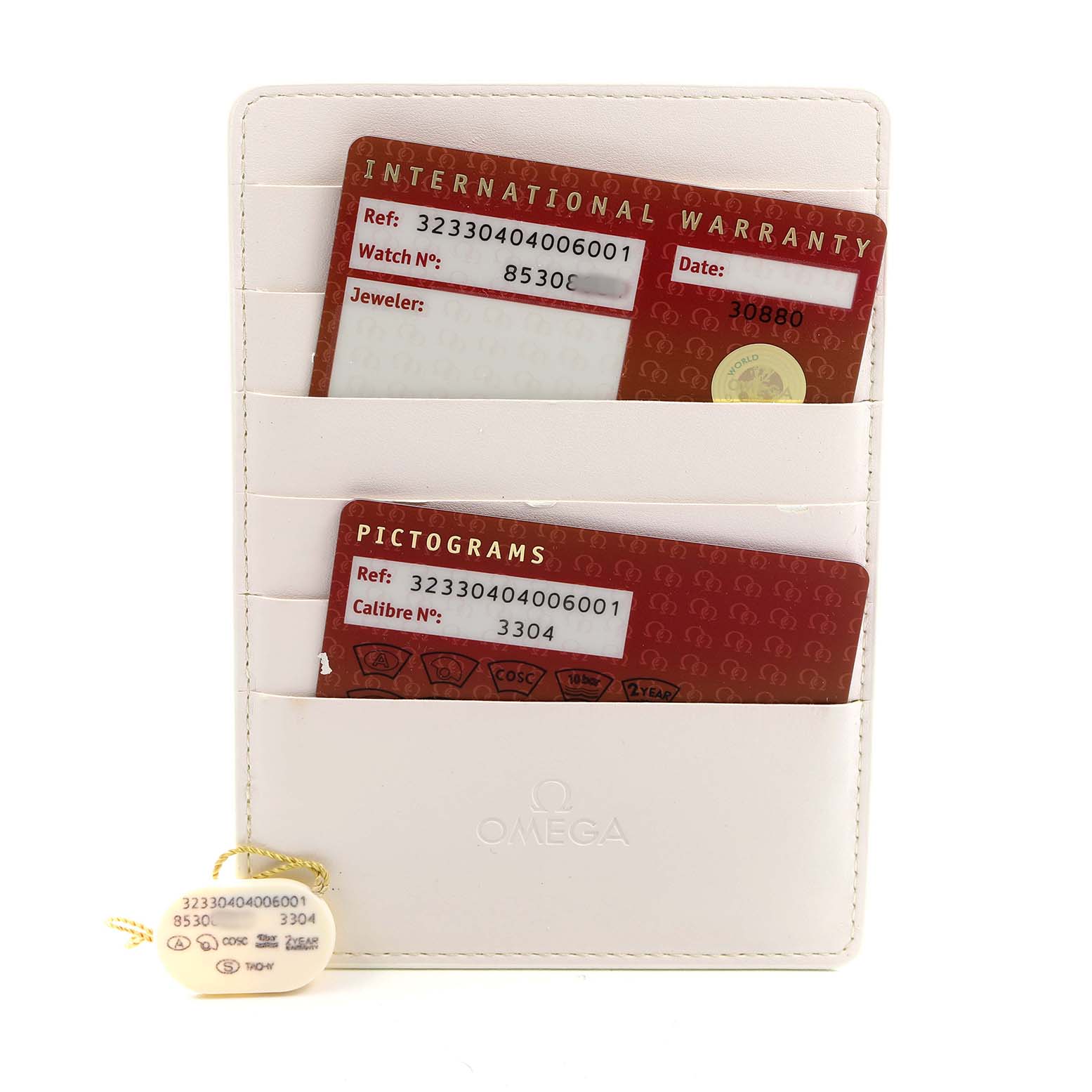 The image shows the warranty cards and a tag for the Omega Speedmaster 323.30.40.40.06.001 Men's Stainless Steel Grey Dial, placed in a white cardholder.