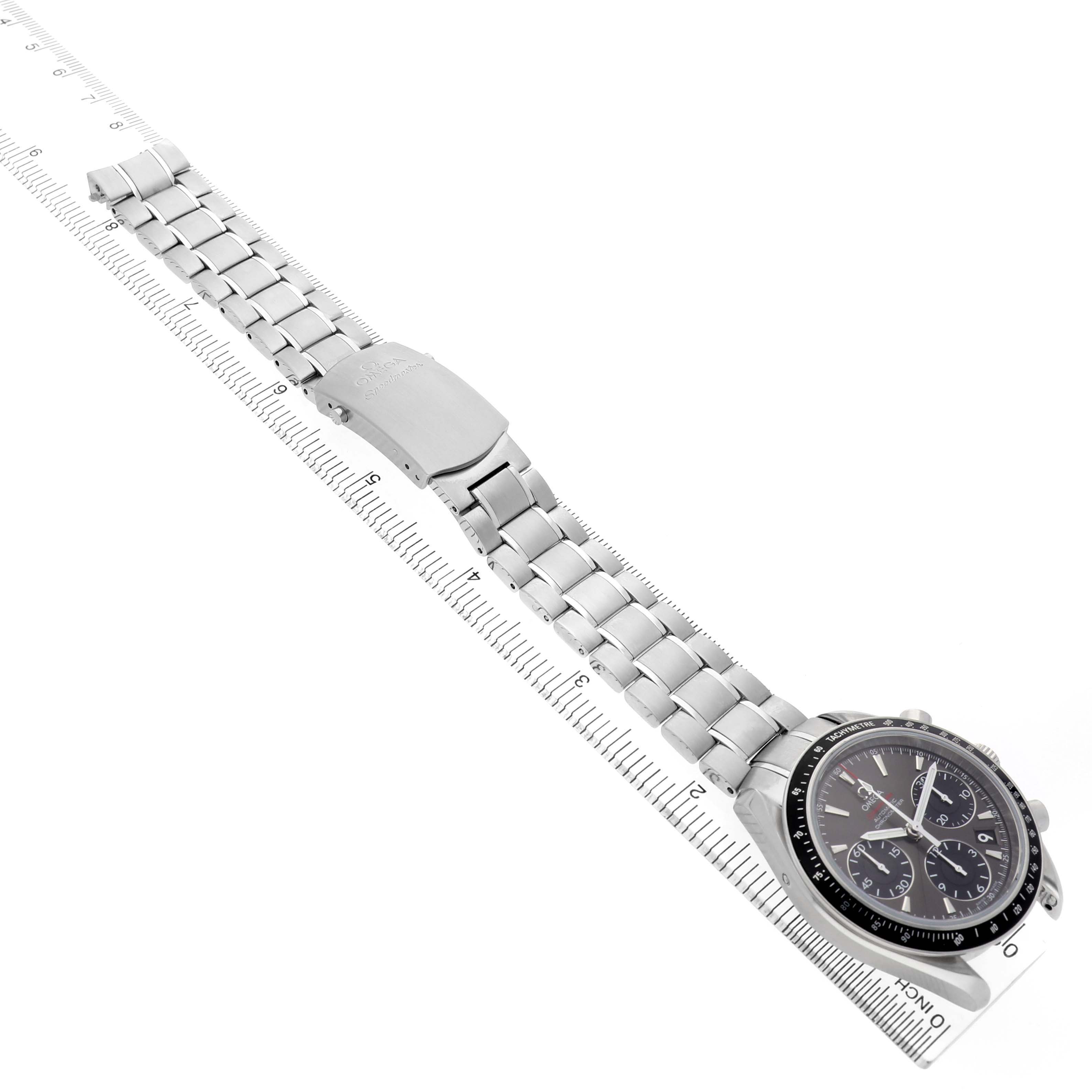 The Omega Speedmaster 323.30.40.40.06.001 Men's Stainless Steel Grey Dial watch is shown at an angle, highlighting its bracelet, clasp, and face against a ruler for scale comparison.