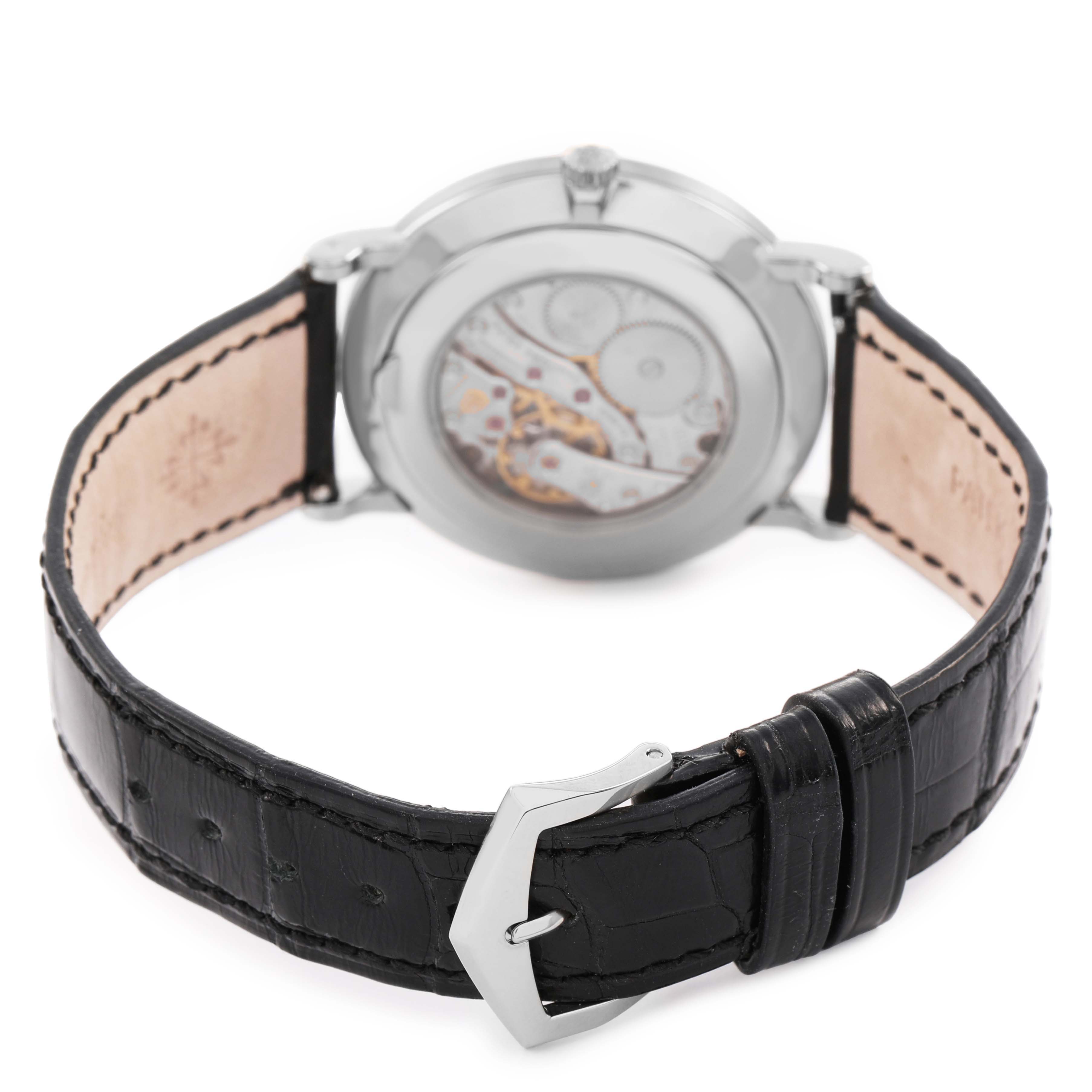 The Patek Philippe Calatrava 5116 Men's White Gold White Dial watch is shown from the back, featuring the movement and black leather strap with a silver buckle.