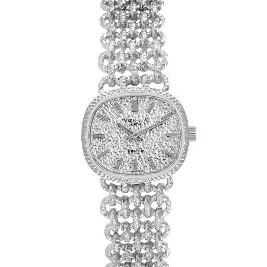 The Patek Philippe Golden Ellipse watch is shown from a top-down angle, displaying its textured dial and linked bracelet.