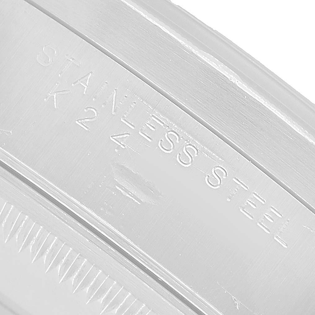 The image shows a close-up of the Rolex Date 15210 Men's Stainless Steel Blue Dial model's case, highlighting the "STAINLESS STEEL" engraving.
