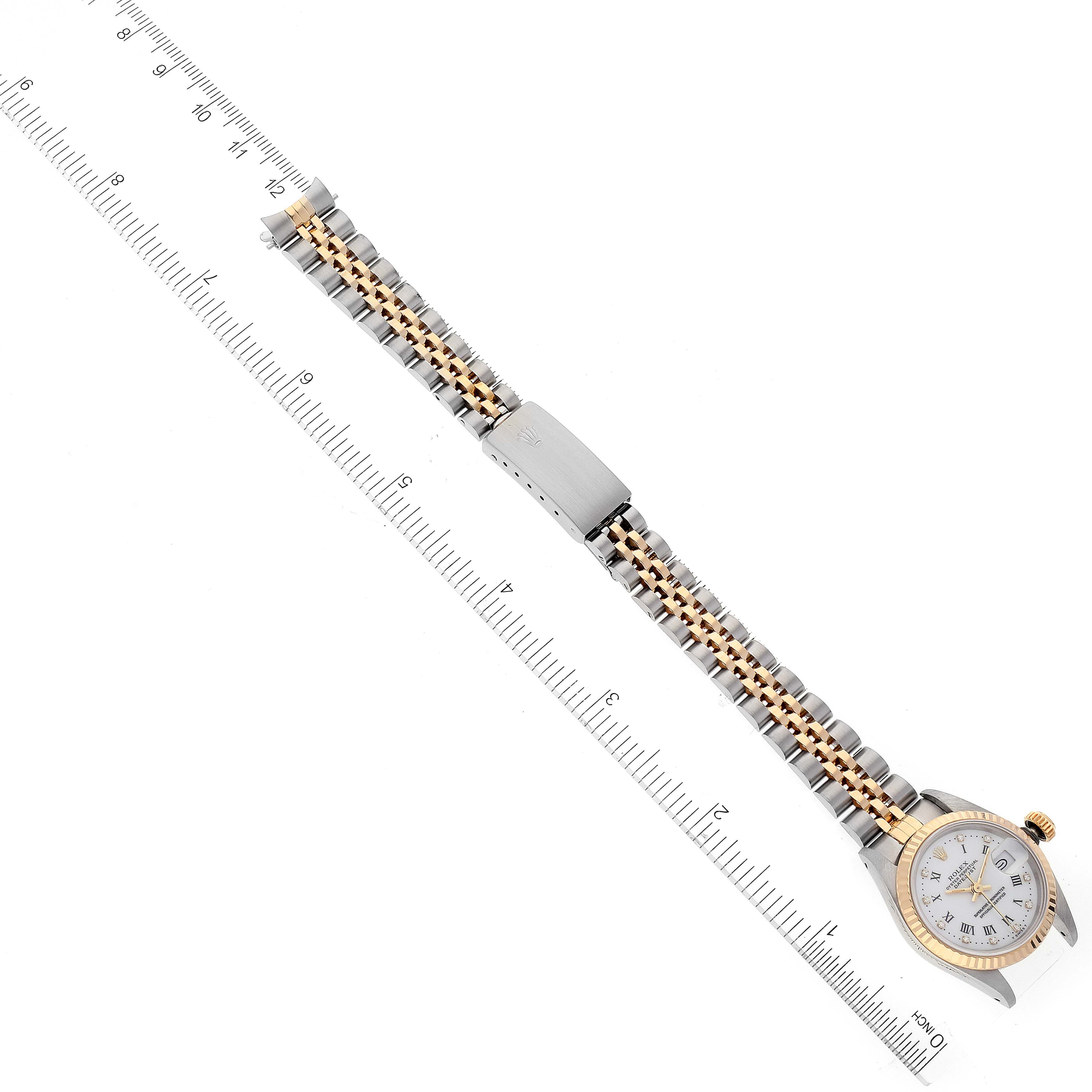 This image shows a Rolex Datejust 69173 Women's Steel and Gold (two tone) White Dial 69173 Women's Steel and Gold (two tone) White Dial watch laid flat, with its band and clasp alongside a ruler for scale.