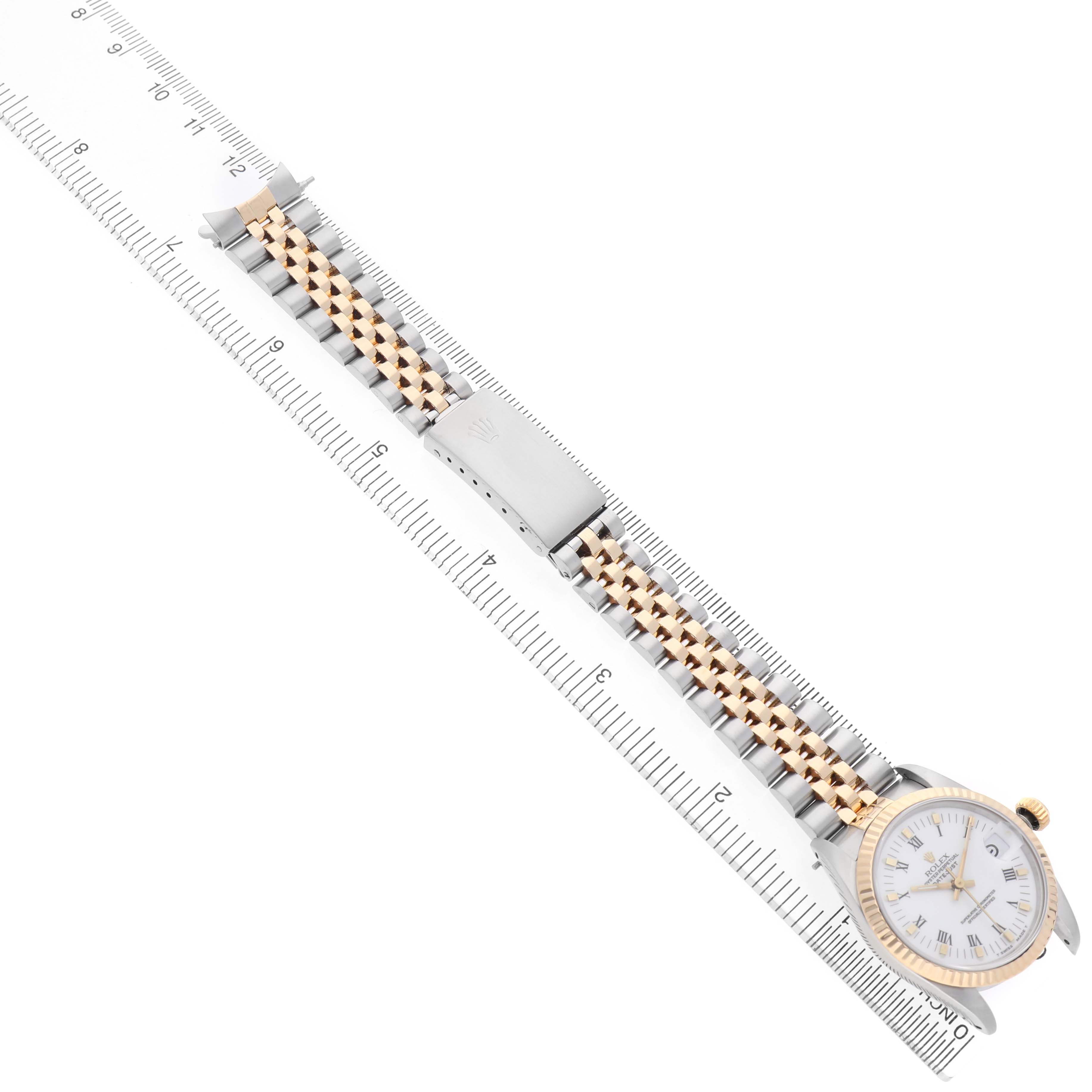 The Rolex Datejust 68273 Women's Stainless Steel White Dial watch is shown from a top-down angle, highlighting the face, bezel, and Jubilee bracelet with a ruler for scale.
