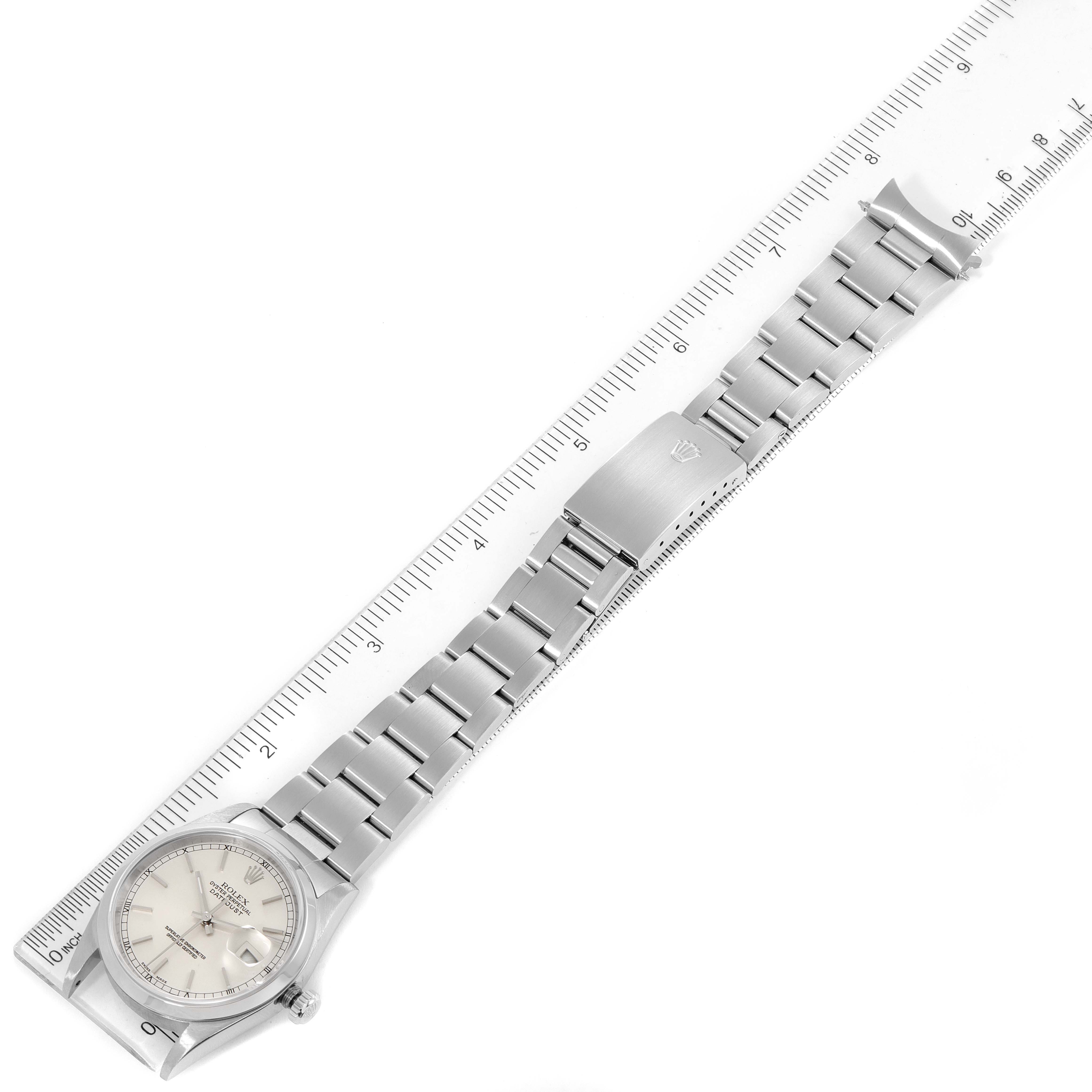 The image shows a Rolex Datejust 16200 Men's Stainless Steel Silver Dial 16200 Men's Stainless Steel Silver Dial watch and its metal bracelet laid flat and next to a ruler.