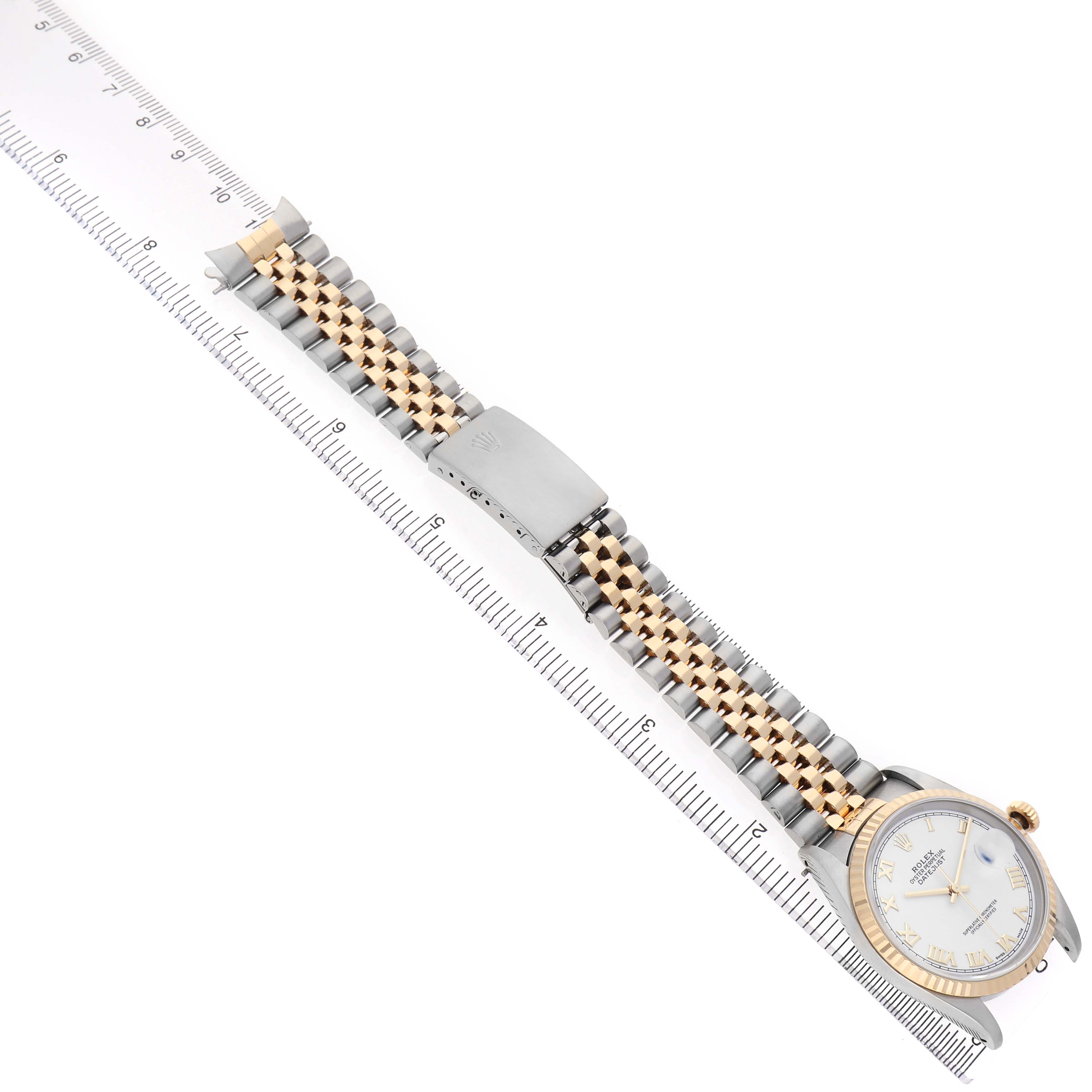 The Rolex Datejust 16233 Men's Steel and Gold (two tone) White Dial watch is shown diagonally, highlighting the two-tone bracelet, clasp, and face alongside a ruler.