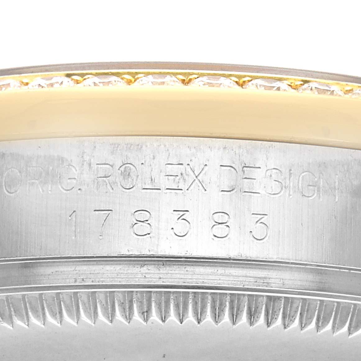 The image shows a close-up of the bezel and case edge of a Rolex Datejust, showcasing engraved design details and diamonds.