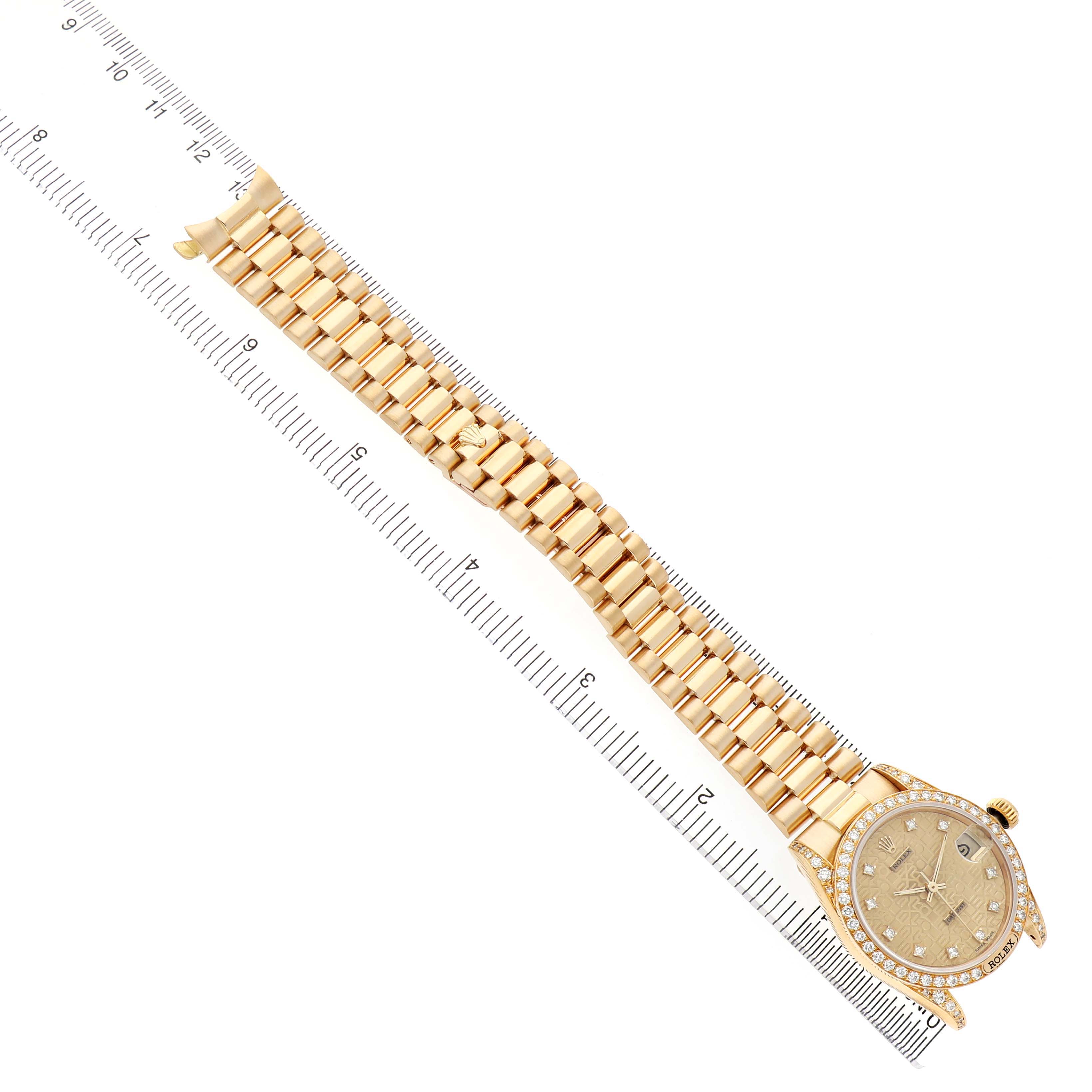 The Rolex President 68158 Women's Yellow Gold Champagne Dial watch is shown at a top-down angle, displaying the full band and face alongside a ruler for scale.