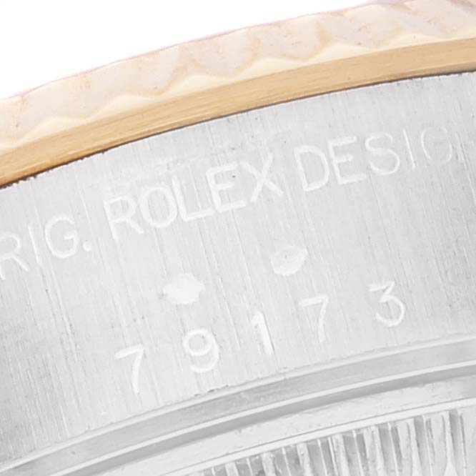 This close-up image shows the side of the case with engraved text and the bezel of a Rolex Datejust 79173 Women's Steel and Gold (two tone) Silver Dial 79173 Women's Steel and Gold (two tone) Silver Dial model watch.