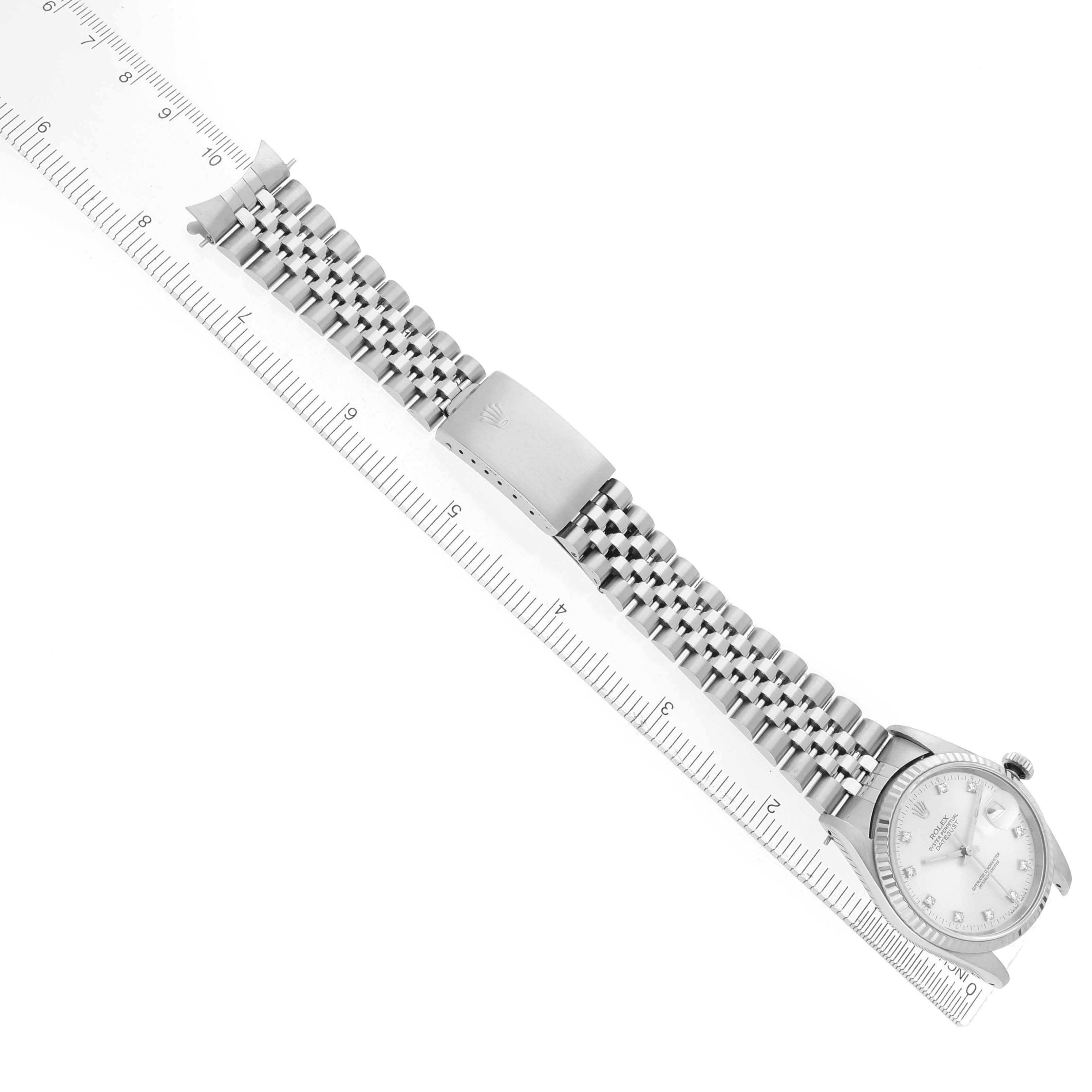 The Rolex Datejust 16234 Men
s Stainless Steel Silver Dial 16234 Men
s Stainless Steel Silver Dial watch is shown from an overhead angle, highlighting the face, bracelet, and clasp next to a ruler for scale.