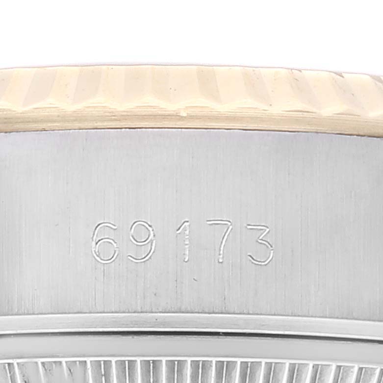 This close-up image shows the side of a Rolex Datejust 69173 Women's Steel and Gold (two tone) Champagne Dial 69173 Women's Steel and Gold (two tone) Champagne Dial model 69173, including part of its fluted bezel and model number engraving.