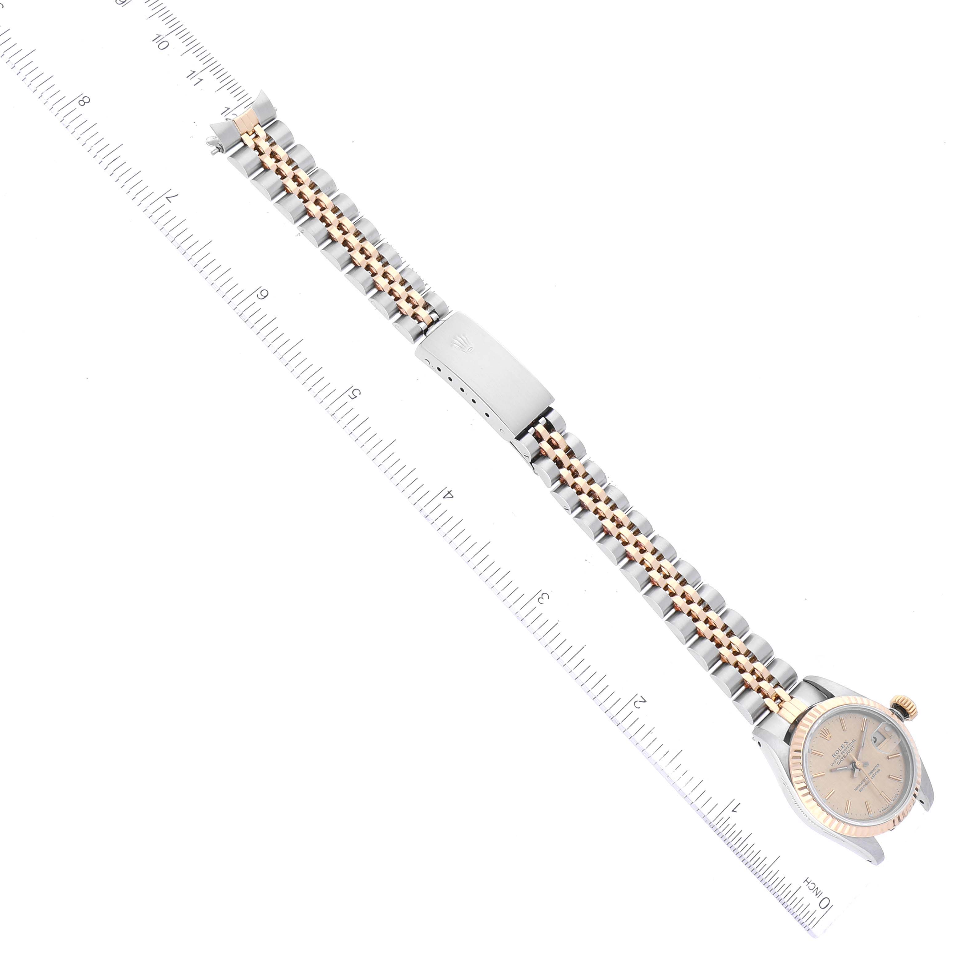 This image shows the Rolex Datejust 69173 Women's Steel and Gold (two tone) Champagne Dial 69173 Women's Steel and Gold (two tone) Champagne Dial watch laid flat with its bracelet extended next to a ruler for scale.