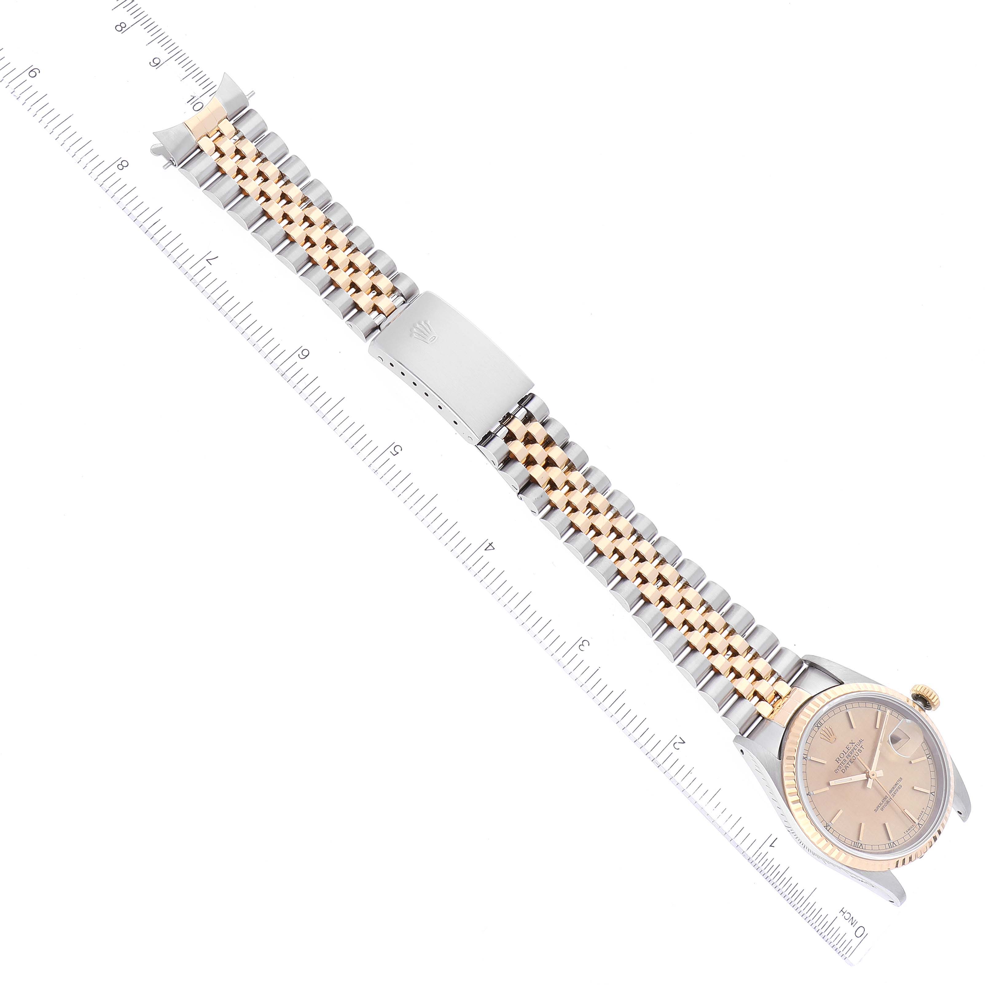 This Rolex Datejust 16233 Men's Steel and Gold (two tone) Champagne Dial 16233 Men's Steel and Gold (two tone) Champagne Dial watch is shown from an overhead angle, displaying the face, bezel, and two-tone bracelet alongside a measuring ruler.