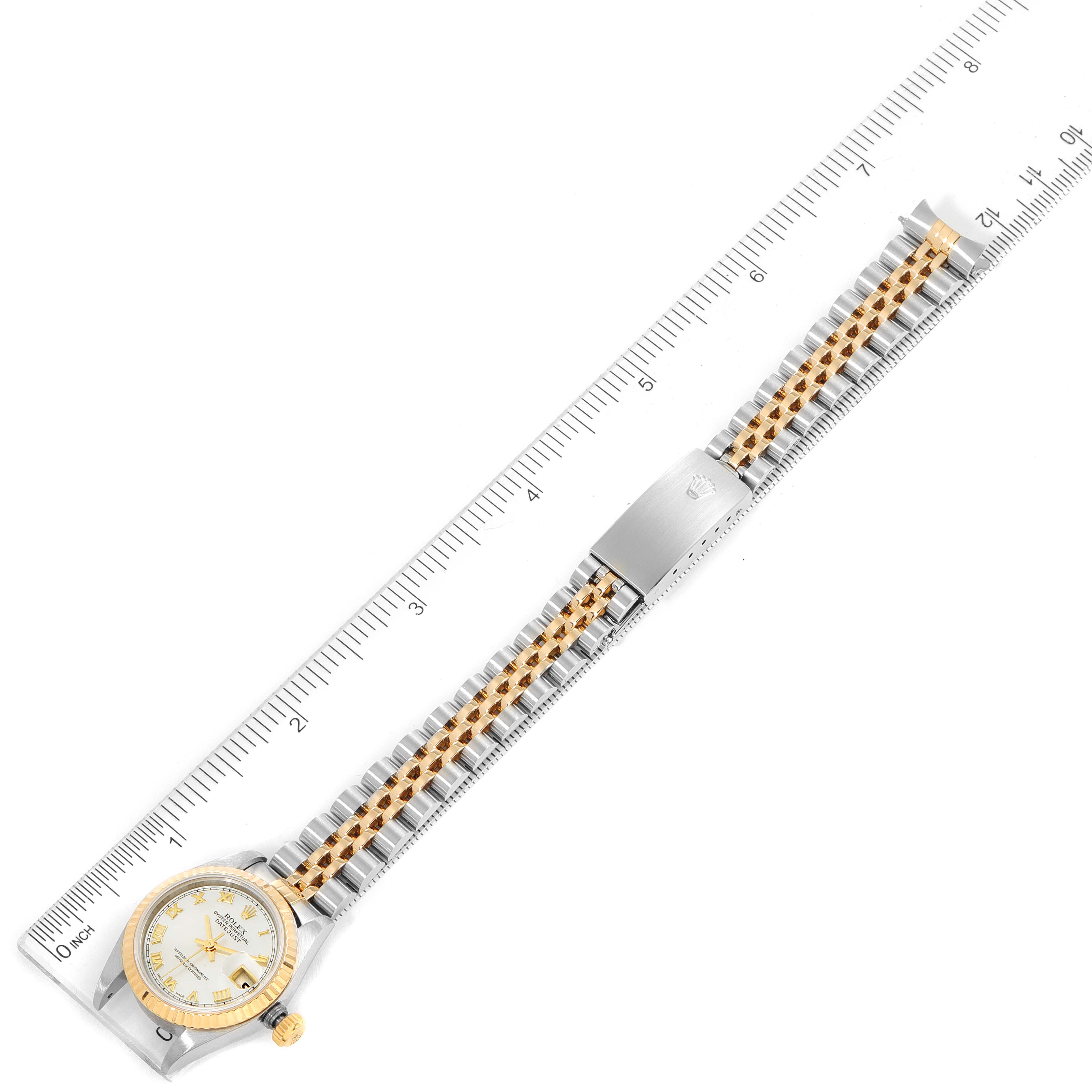 The image shows an aerial view of a Rolex Datejust 79173 Women
s Steel and Gold (two tone) Mother of Pearl Dial 79173 Women
s Steel and Gold (two tone) Mother of Pearl Dial watch, including its face, bezel, and two-tone bracelet with a clasp.