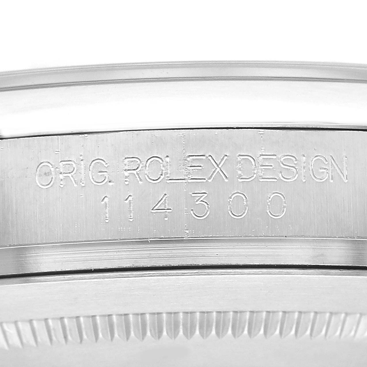 The image shows a close-up of the serial number inscription on the side of a Rolex Oyster Perpetual 114300 Men's Stainless Steel Blue Dial watch case.
