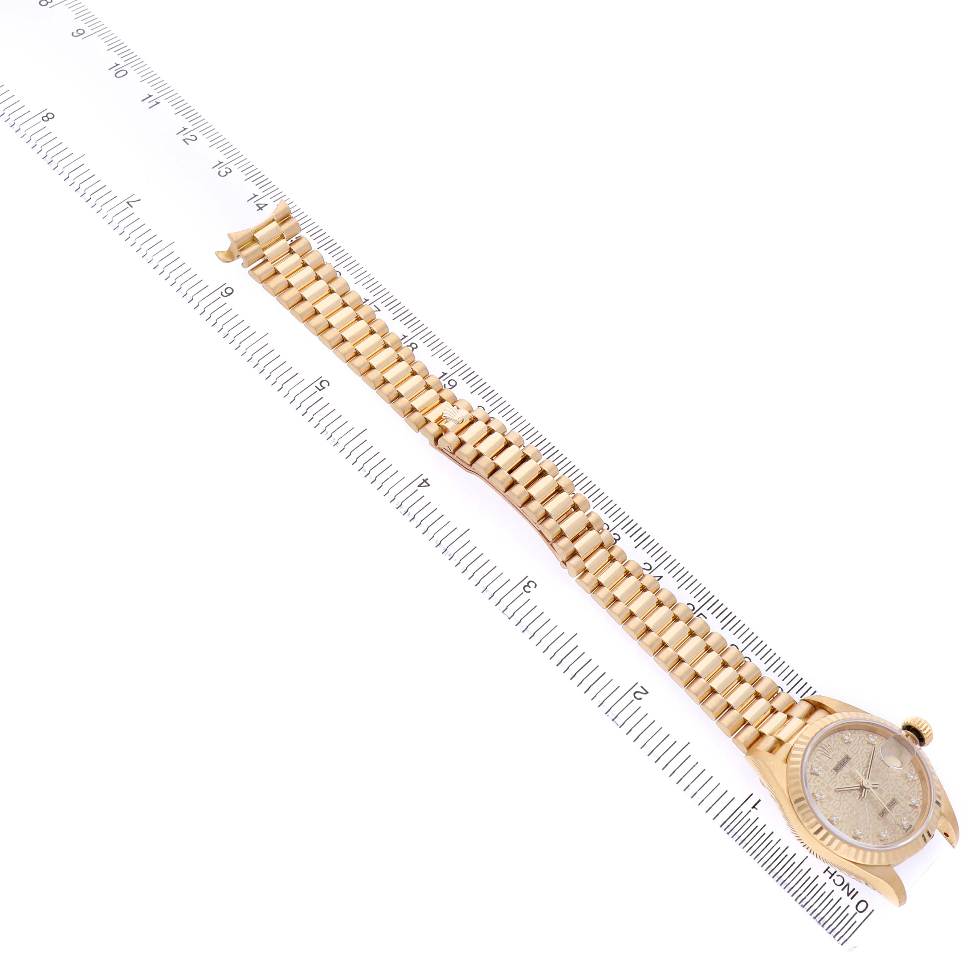 The Rolex President 69178 Women's Yellow Gold Champagne Dial watch is shown from a top view, displaying the full bracelet and face alongside a ruler for scale.