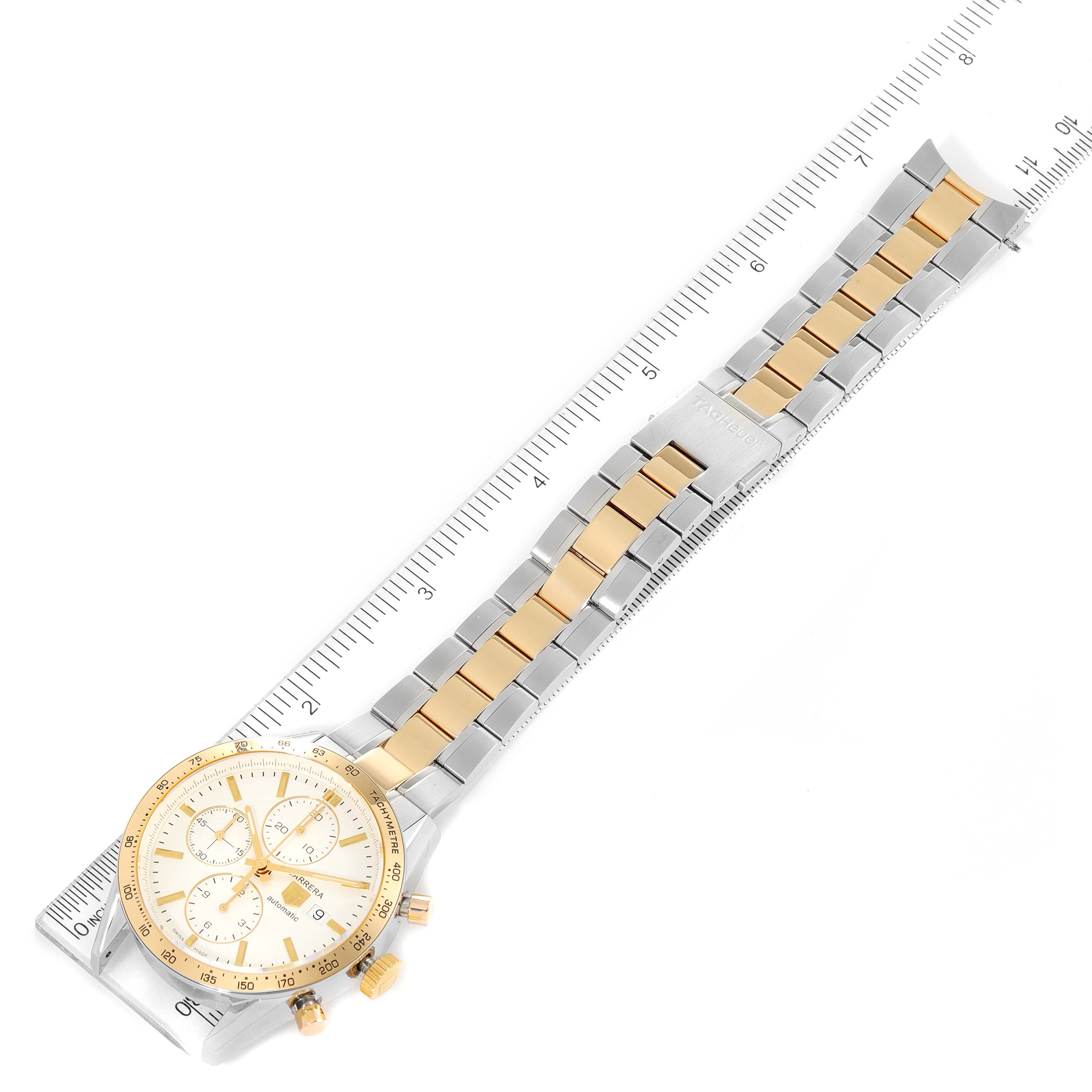 The Tag Heuer Carrera CV2050.BD0789 Men's Steel and Gold (two tone) Silver Dial CV2050.BD0789 Men's Steel and Gold (two tone) Silver Dial watch is shown from a top-down angle, displaying its face, gold bezel, two-tone bracelet, and side buttons; it is placed on a ruler.