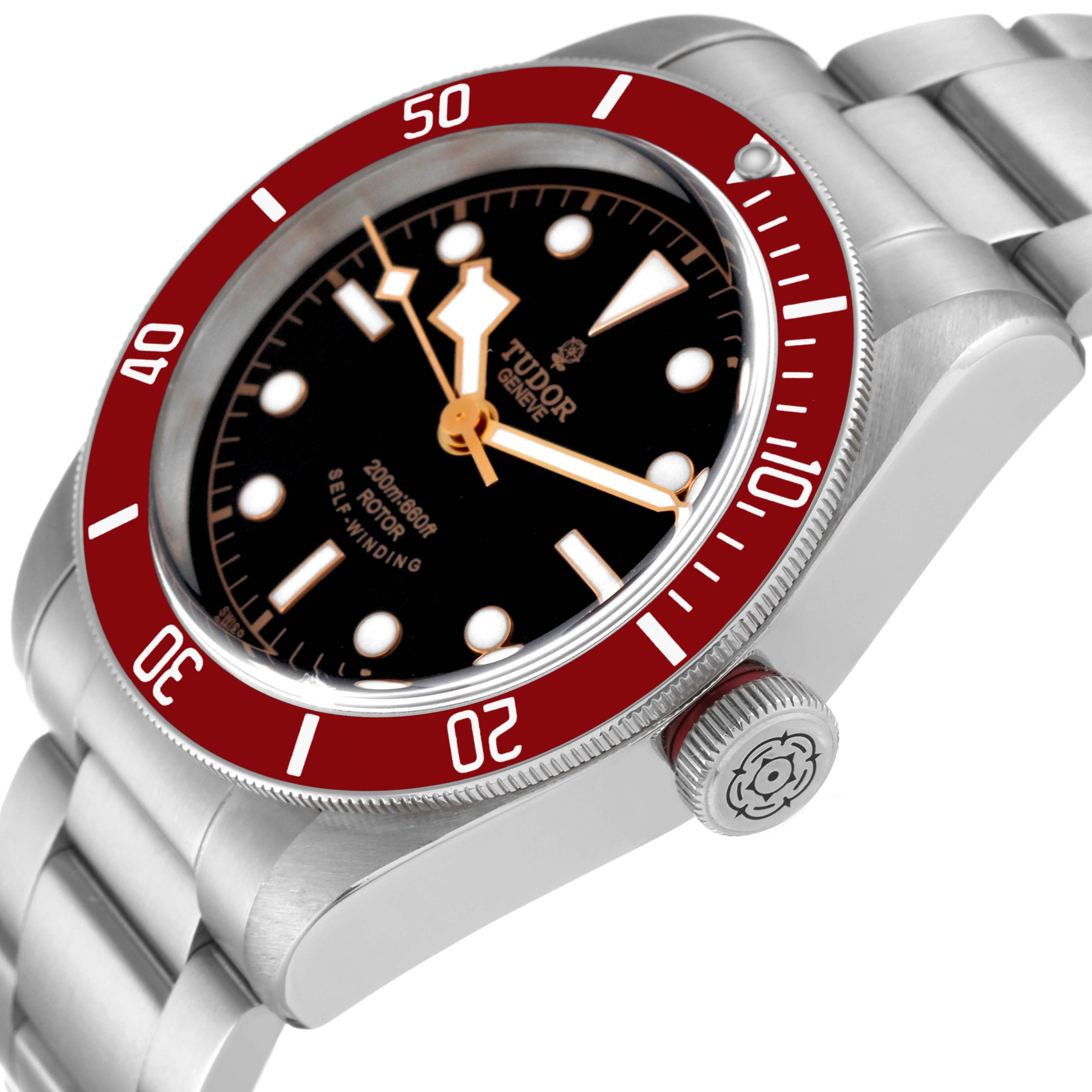 The image shows a Tudor Heritage Black Bay 79220R Men
s Stainless Steel Black Dial 79220R Men
s Stainless Steel Black Dial watch angled to display its black dial, red bezel, and part of the stainless steel bracelet.