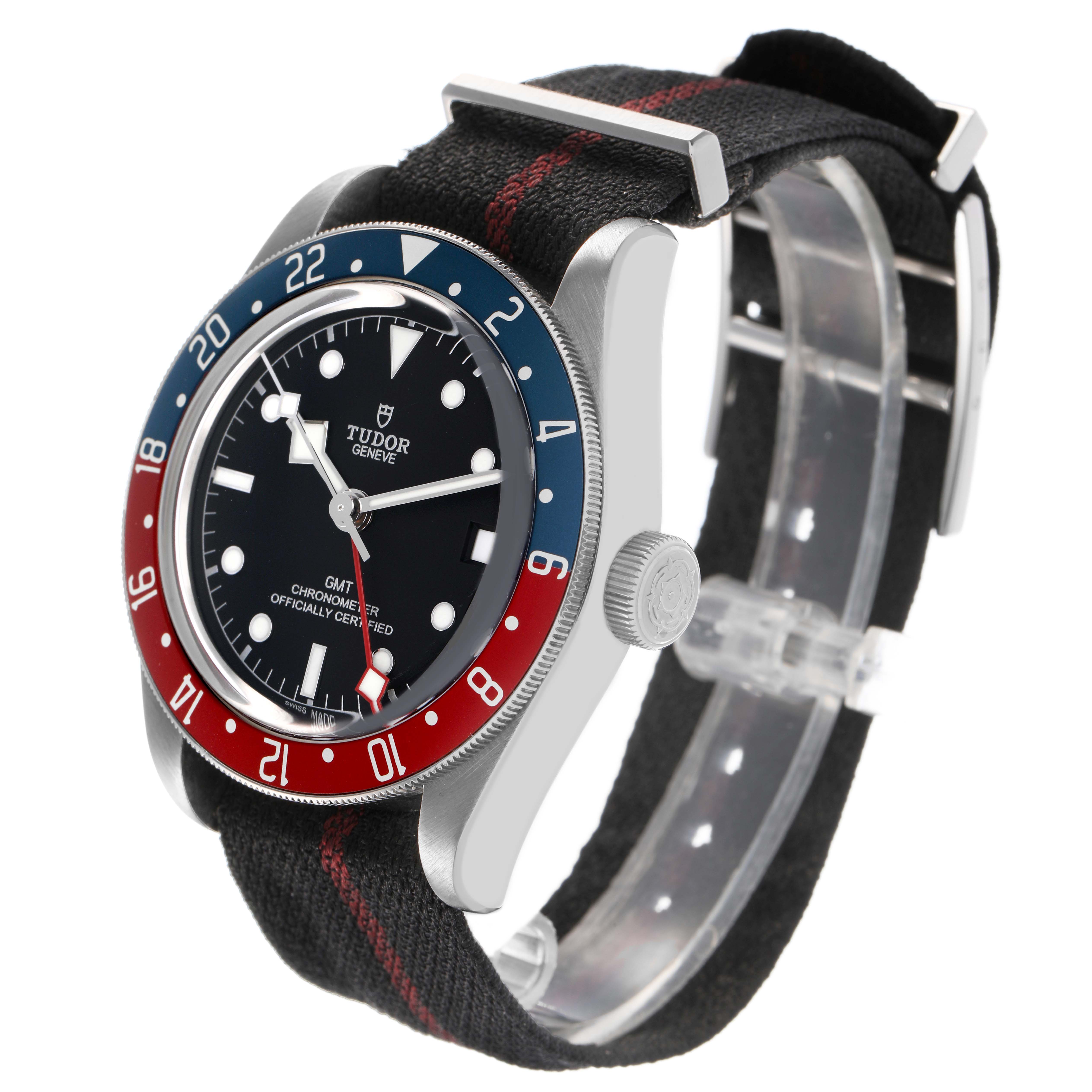 The Tudor Heritage Black Bay 79830RB Men's Stainless Steel Black Dial watch is shown at a three-quarter angle, displaying its bezel, dial, crown, and fabric strap.